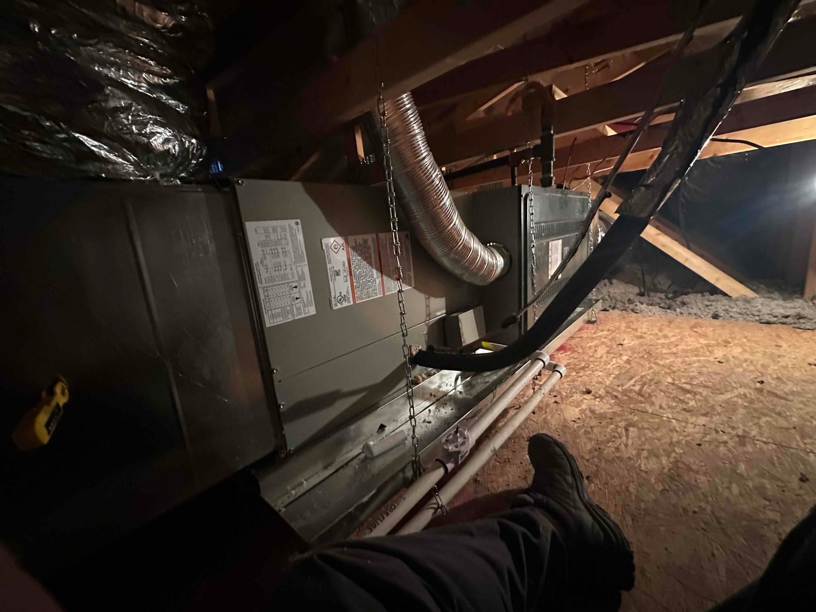 New attic air handler installed on a suspended platform with insulated ducts, condensate drain lines, and sealed refrigerant line set.