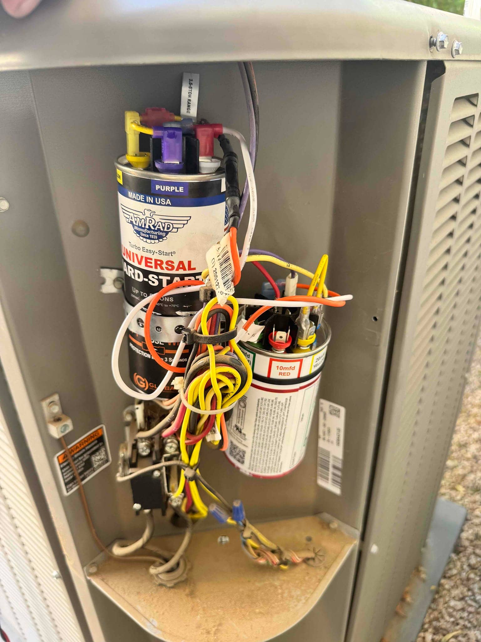 New dual-run capacitor and hard-start kit installed inside the condenser panel, with labeled wiring connected to contactor and terminals.