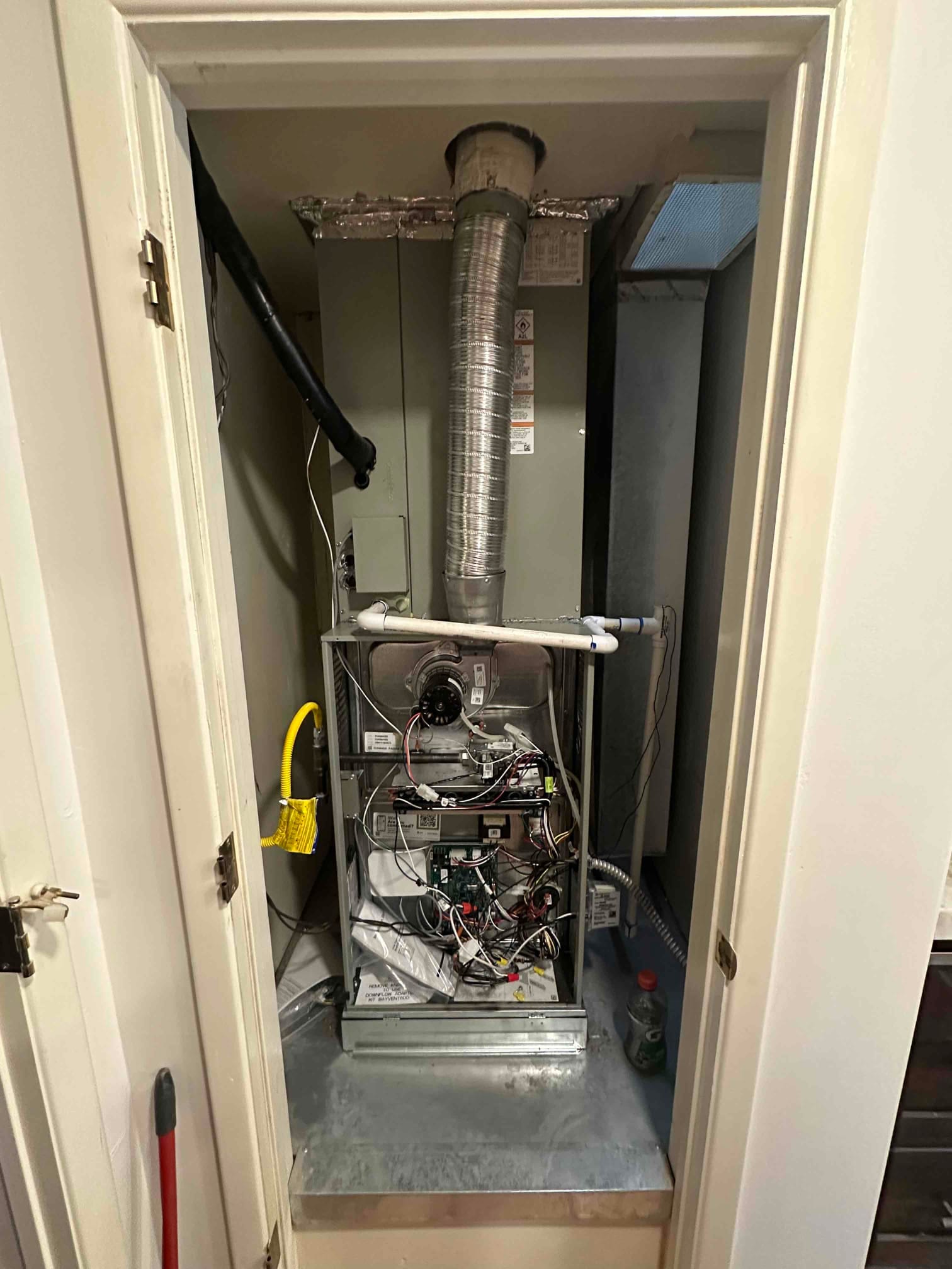 New gas furnace and evaporator coil installed in a closet, with venting, drain, gas flex, and electrical connections visible.