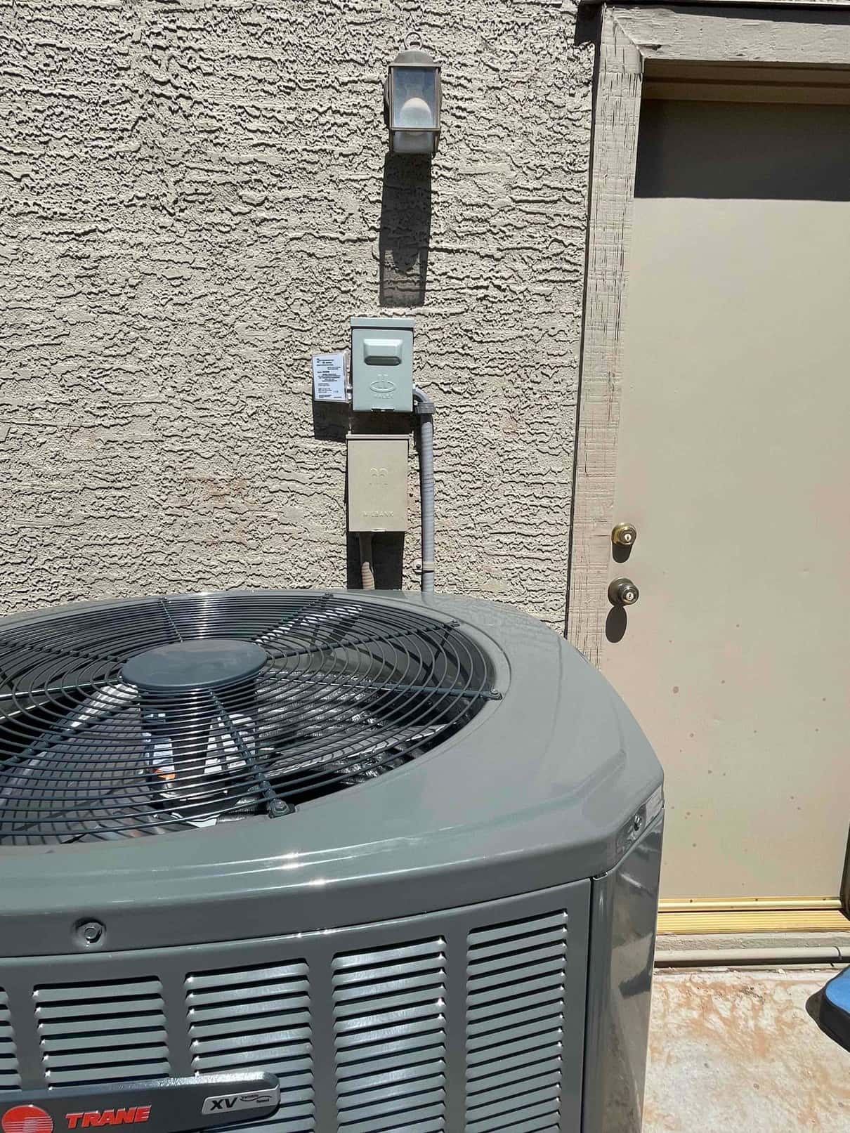New outdoor condenser installed on pad with nearby service disconnect and sealed wall penetration at the installation site.