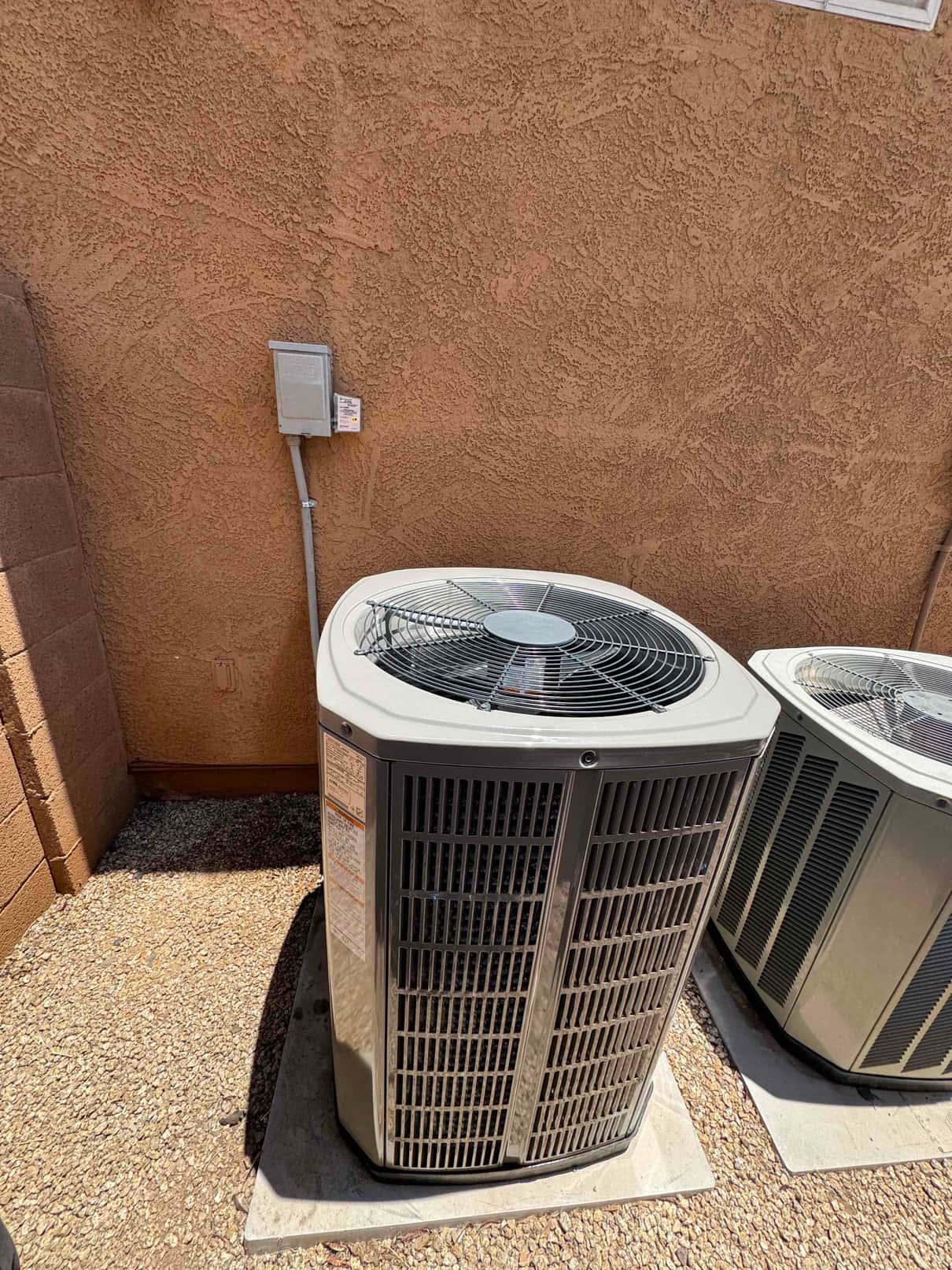 New outdoor condenser set on a level pad with electrical disconnect mounted on the wall and insulated line set installed.