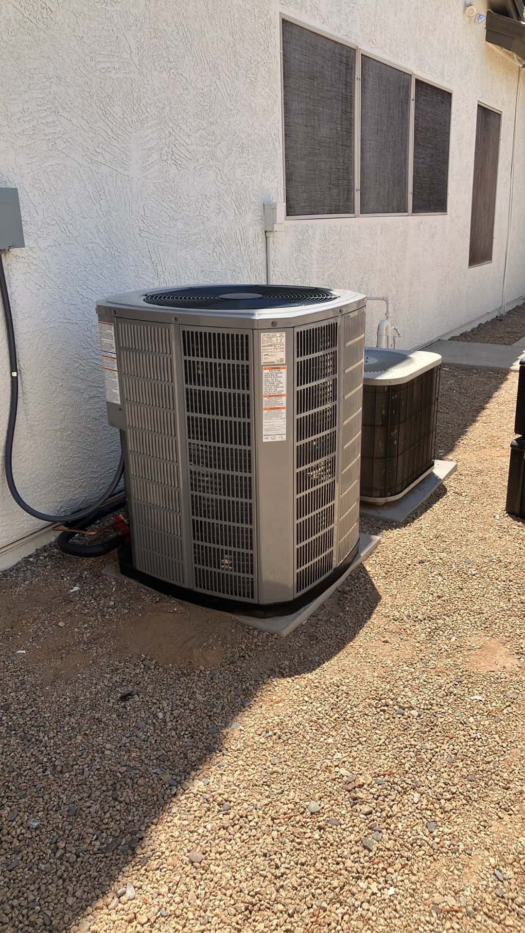 New outdoor condenser set on a level pad with insulated line set and disconnect mounted on the wall.