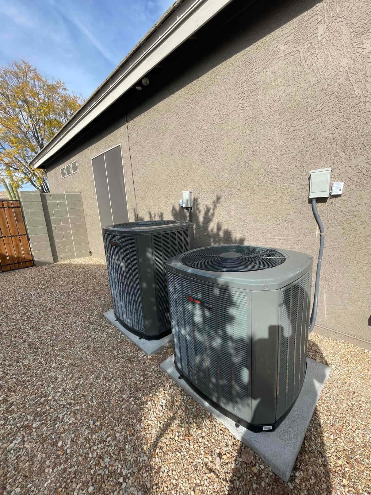 Two new outdoor condensers set on level pads with electrical disconnects mounted on the wall and sealed line set penetrations.