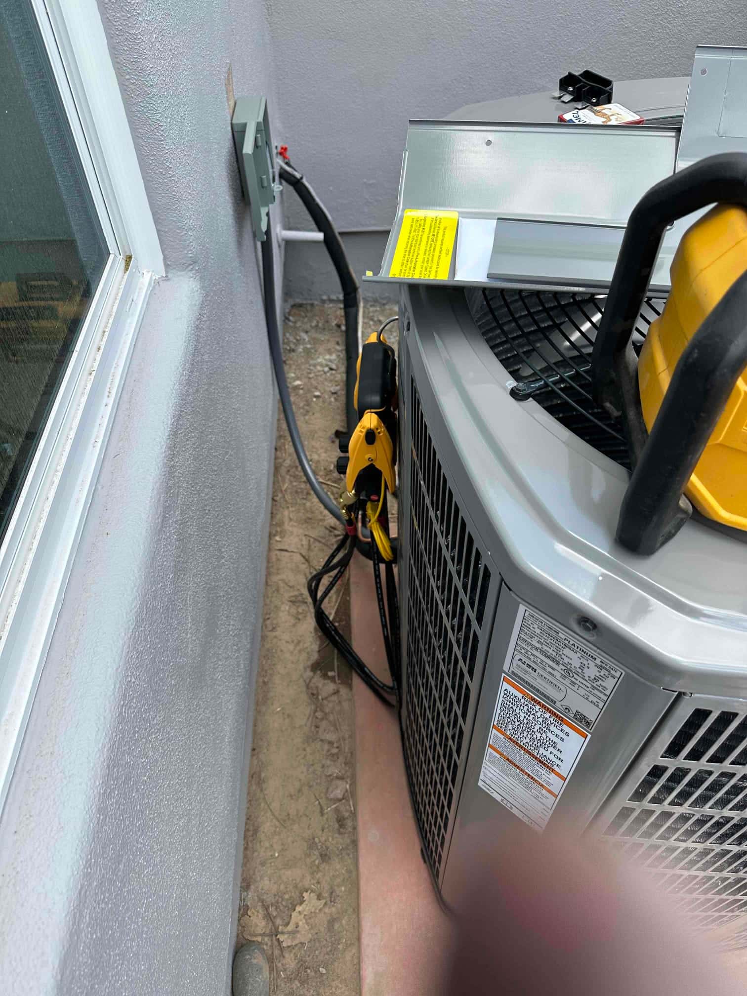 New outdoor heat pump set on a level pad with electrical disconnect, sealed line set penetration, and insulated refrigerant lines routed to the unit.