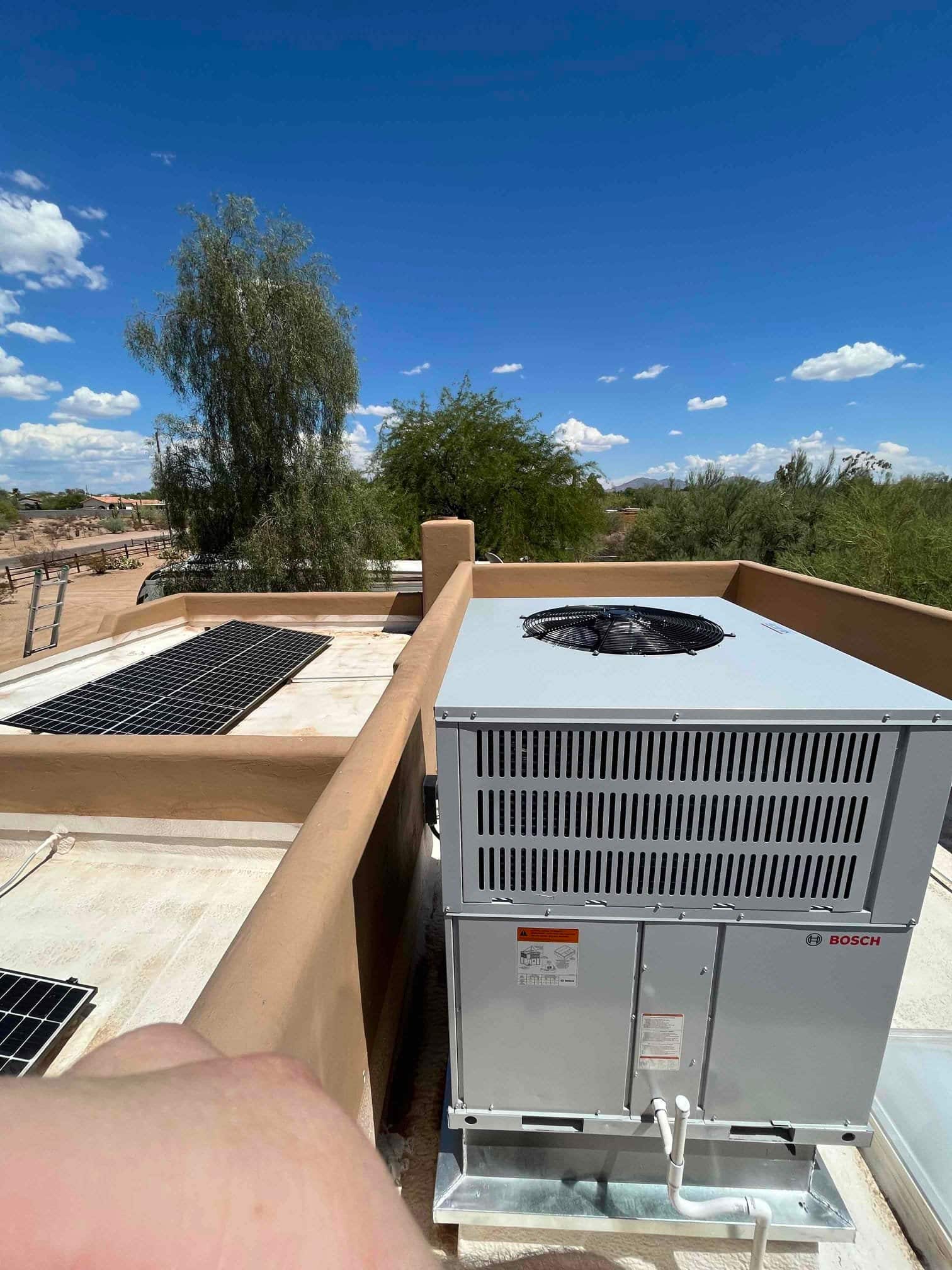 New rooftop package heat pump set on a curb with condensate piping connected and service panels accessible.