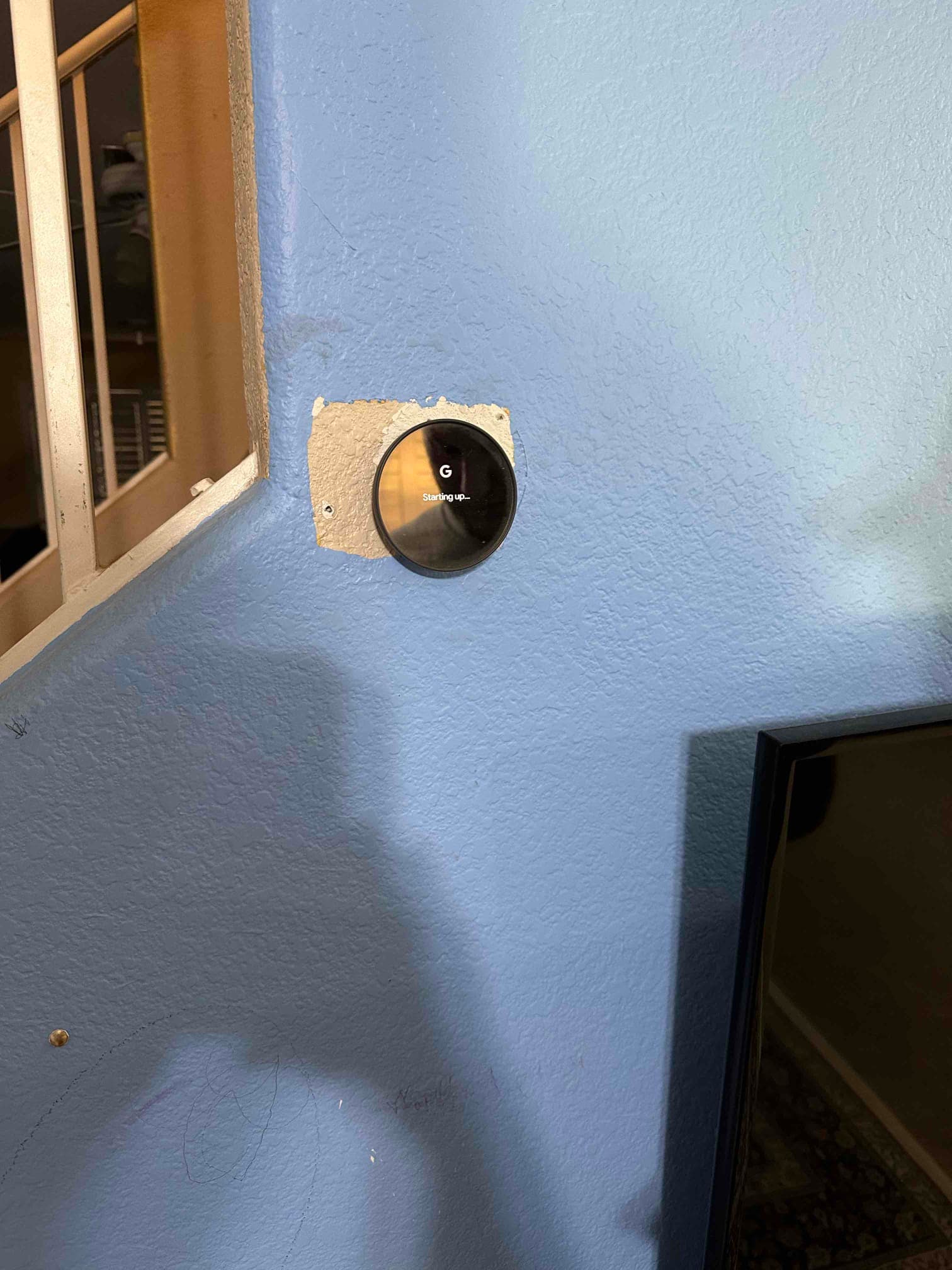 New smart thermostat mounted on the wall, powering on with a startup message after installation.