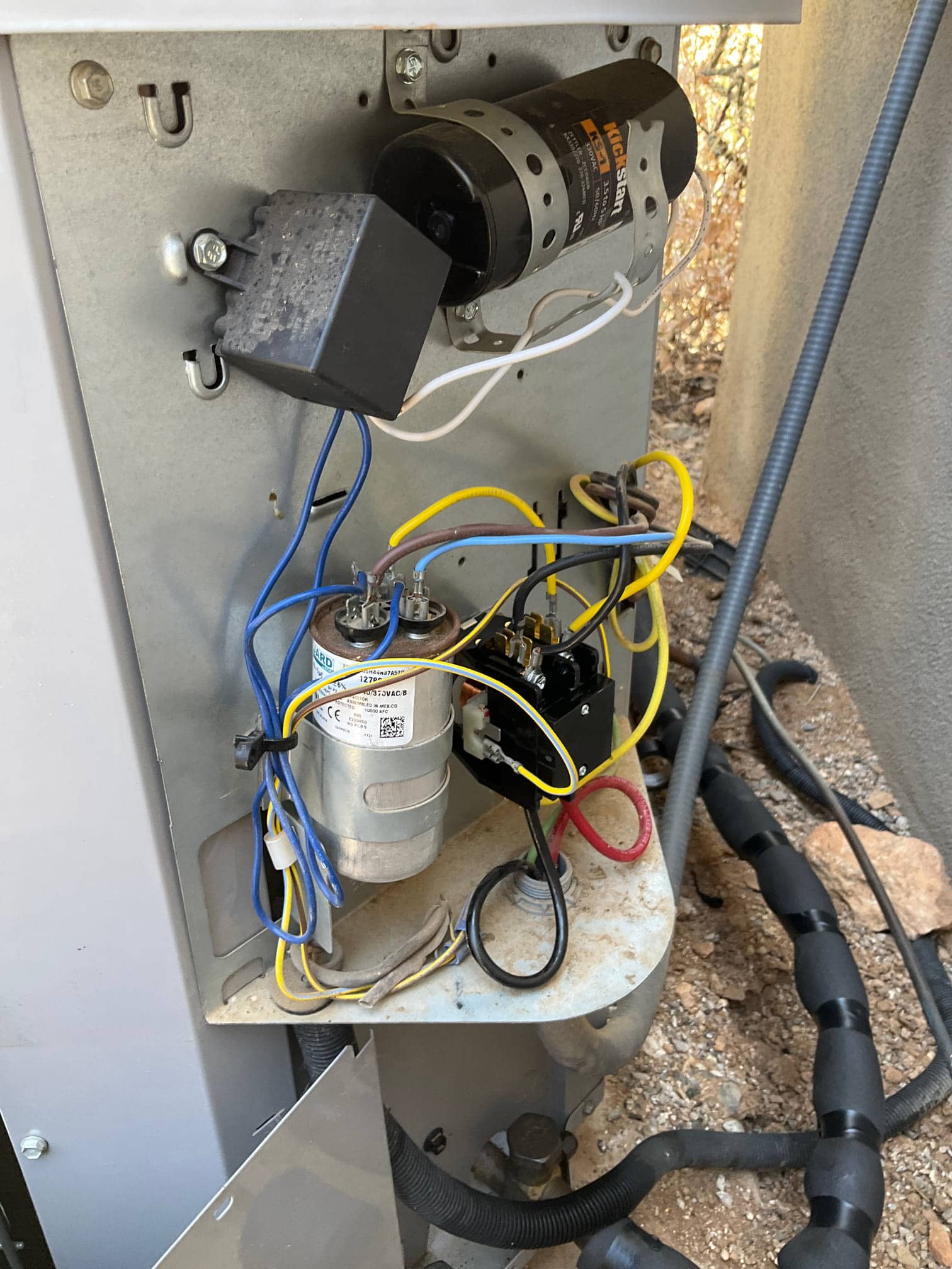 Open outdoor unit control compartment with capacitors, contactor, relay, the customer connected wiring visible.