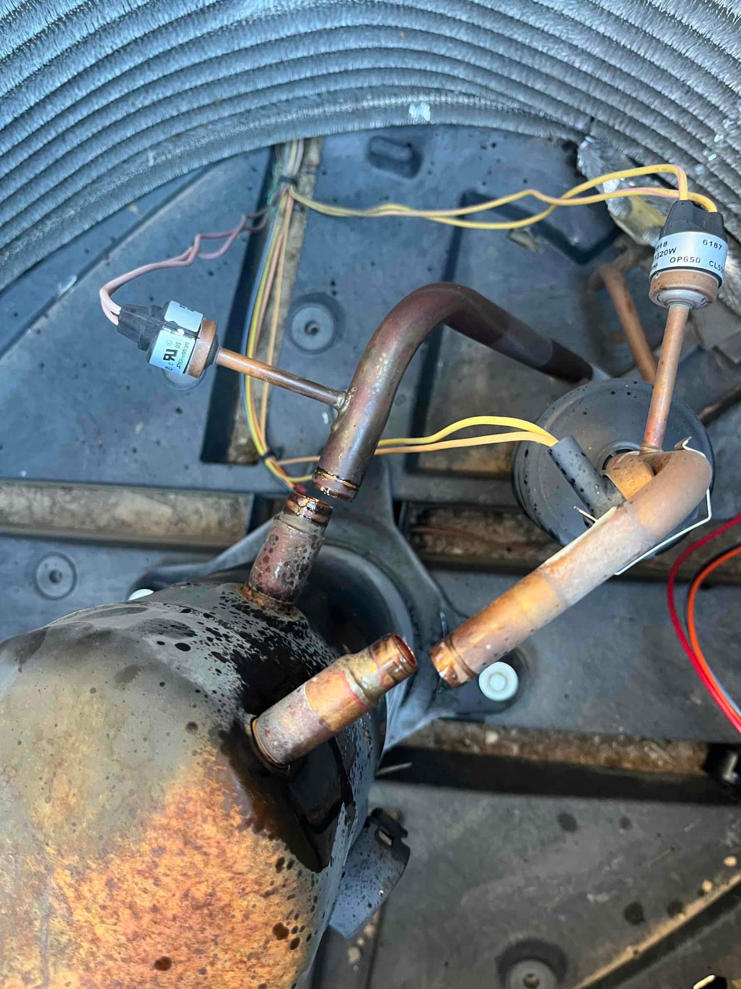 Outdoor condenser compartment showing compressor tubing and newly brazed bi-flow filter drier with connected pressure or temperature sensors and wiring.