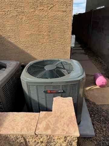 Outdoor condenser set on a level pad beside the house, with clear airflow around the unit and protected line set.