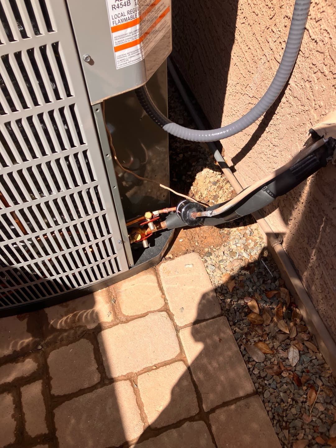 Outdoor condenser set on a level pad with insulated refrigerant lines and electrical whip connected at the service panel.
