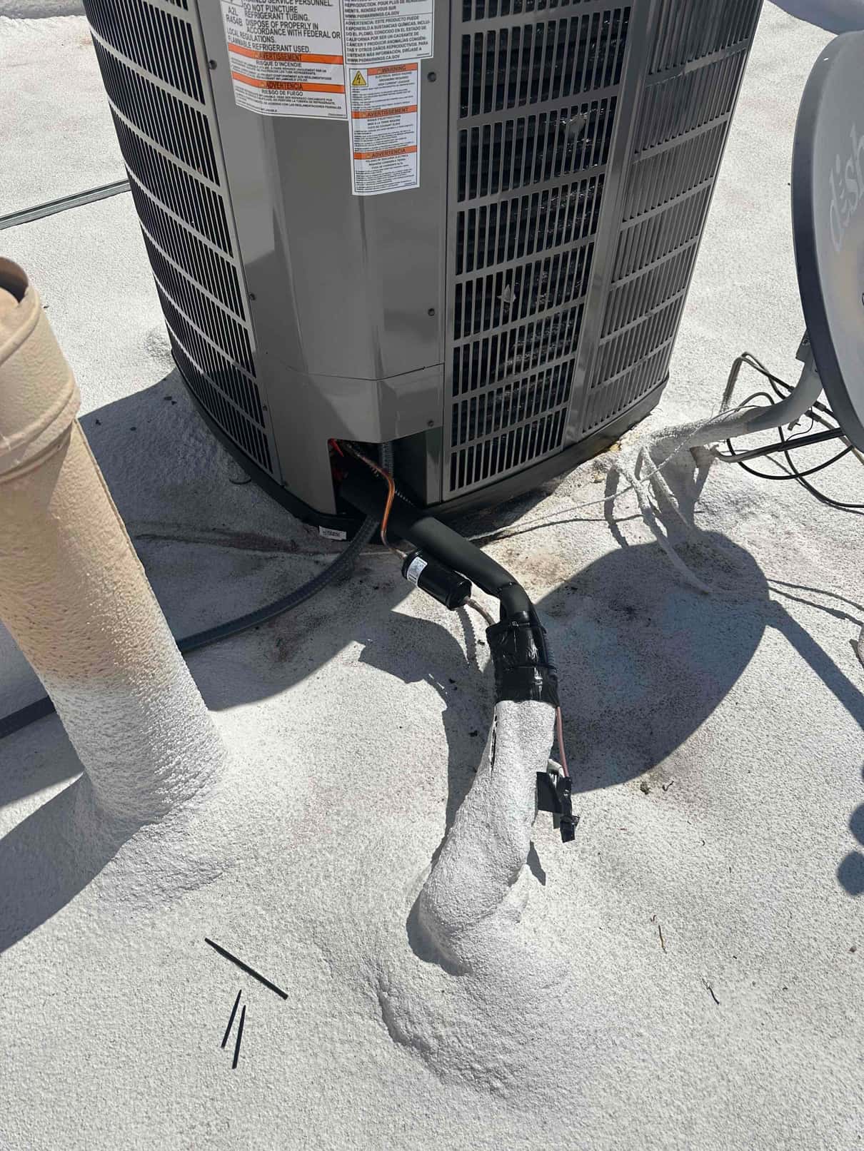 Outdoor condenser set on rooftop with insulated refrigerant line set and electrical whip entering the cabinet through the service port.