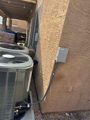 Two outdoor condensers set on pads with weatherproof disconnects and armored whip connections mounted on the exterior wall.