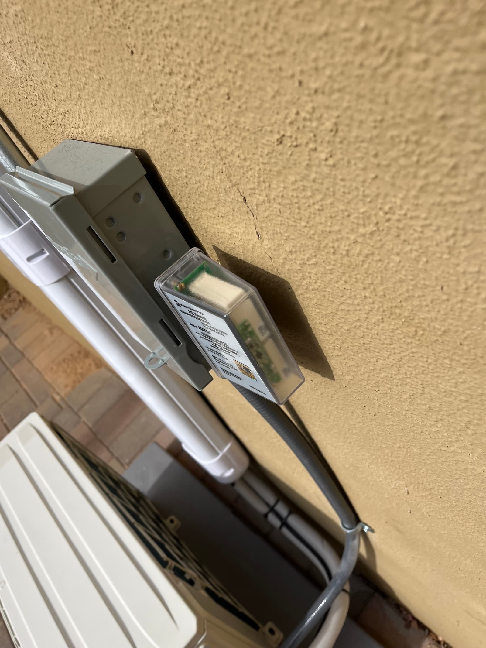 Outdoor disconnect and flexible conduit mounted beside line-set cover above the new heat pump condenser on a level pad.