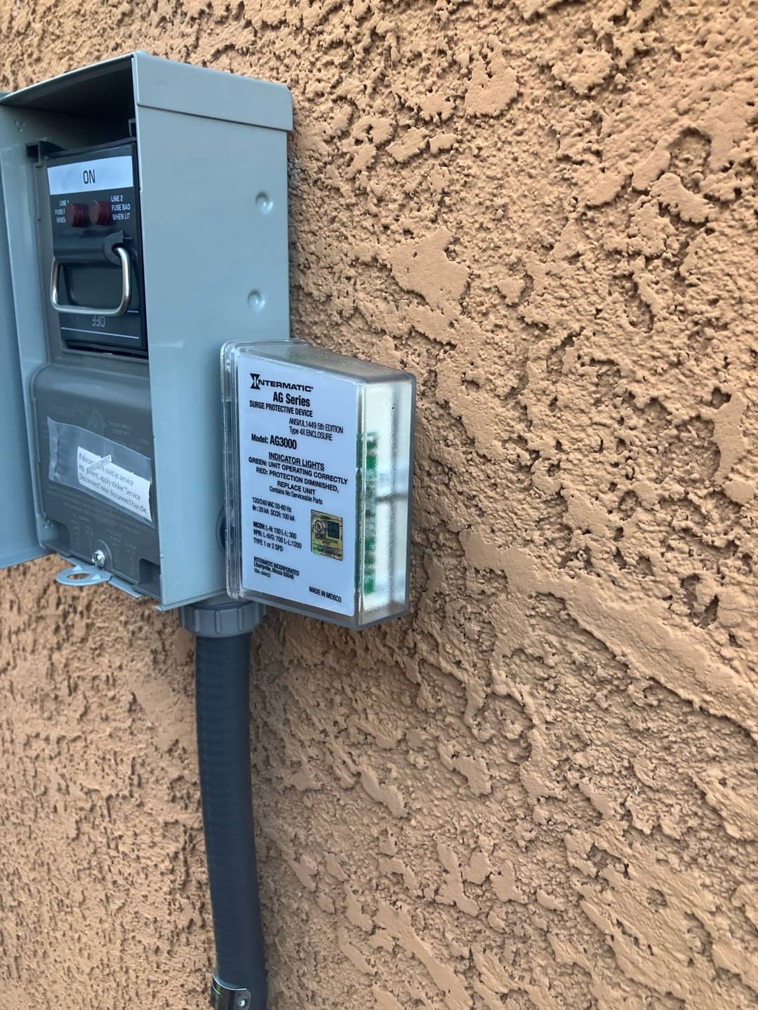 Outdoor HVAC disconnect with surge protective device installed on stucco wall, conduit neatly routed for the new condenser.