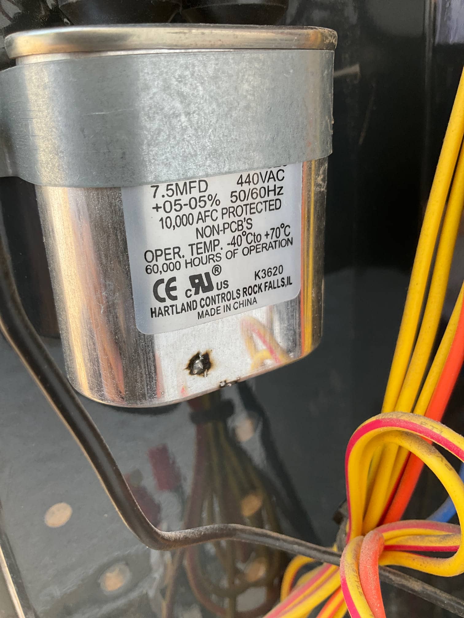 Single run capacitor labeled 7.5 MFD 440VAC with connected wiring and a small burn mark on the can.