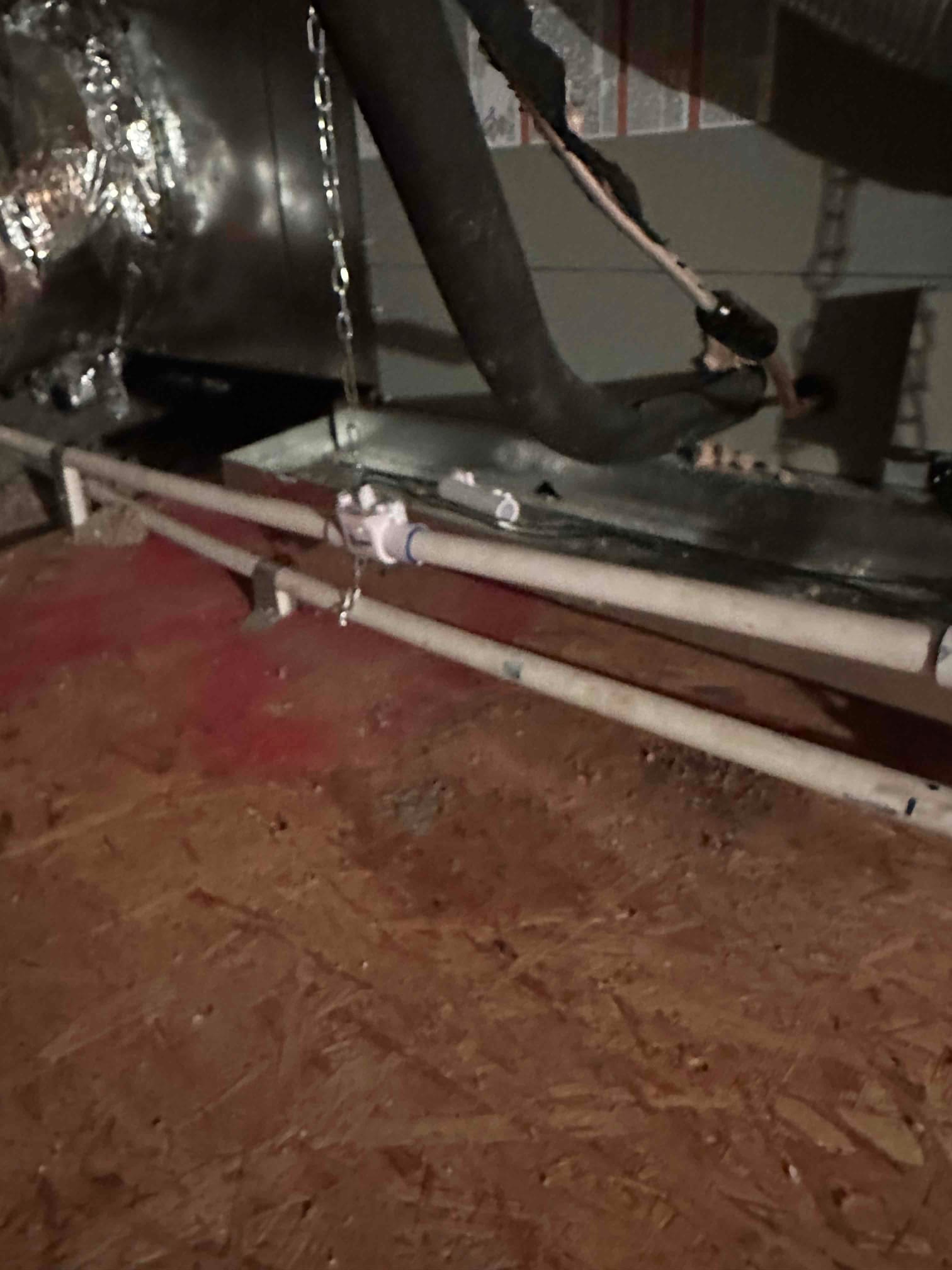 Suspended air handler with insulated refrigerant lines and newly installed PVC condensate drain with cleanout fitting in the attic.