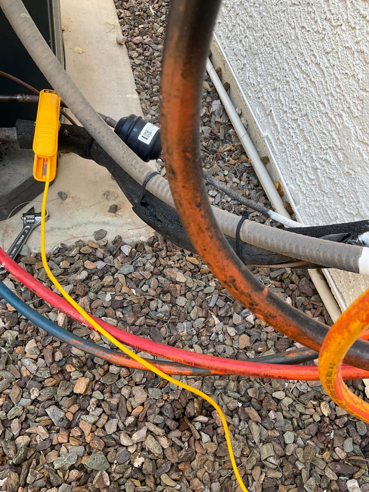 Temperature clamp attached to the copper refrigerant line at the outdoor unit with manifold hoses connected.