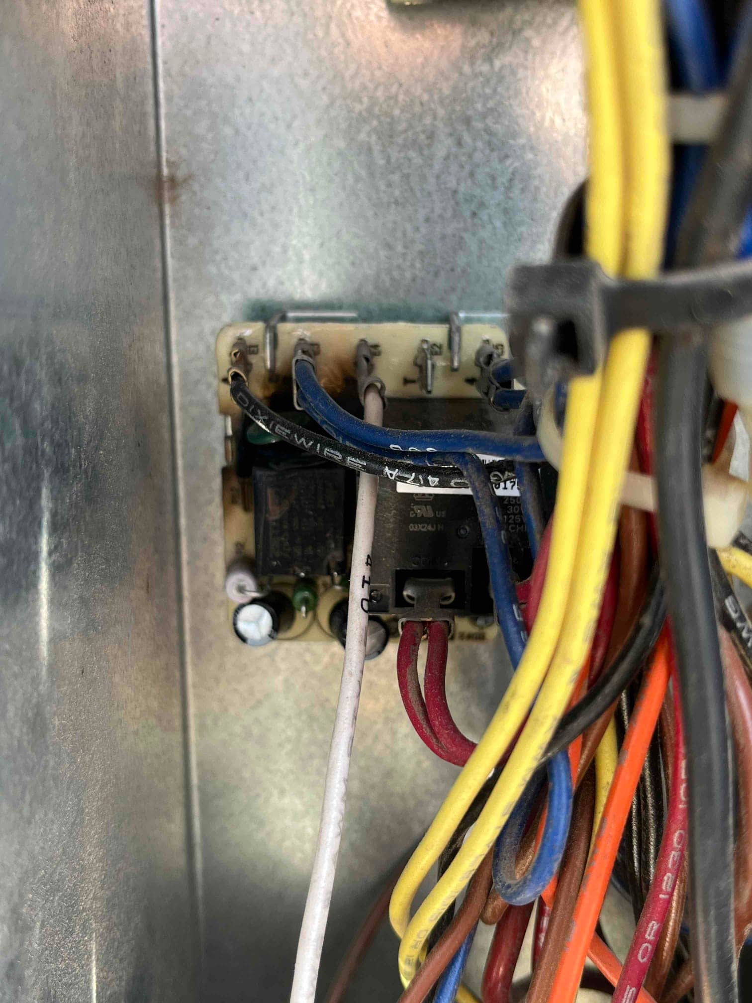 Time delay relay inside an air conditioner control compartment with connected yellow, blue, white, red, and orange wires.
