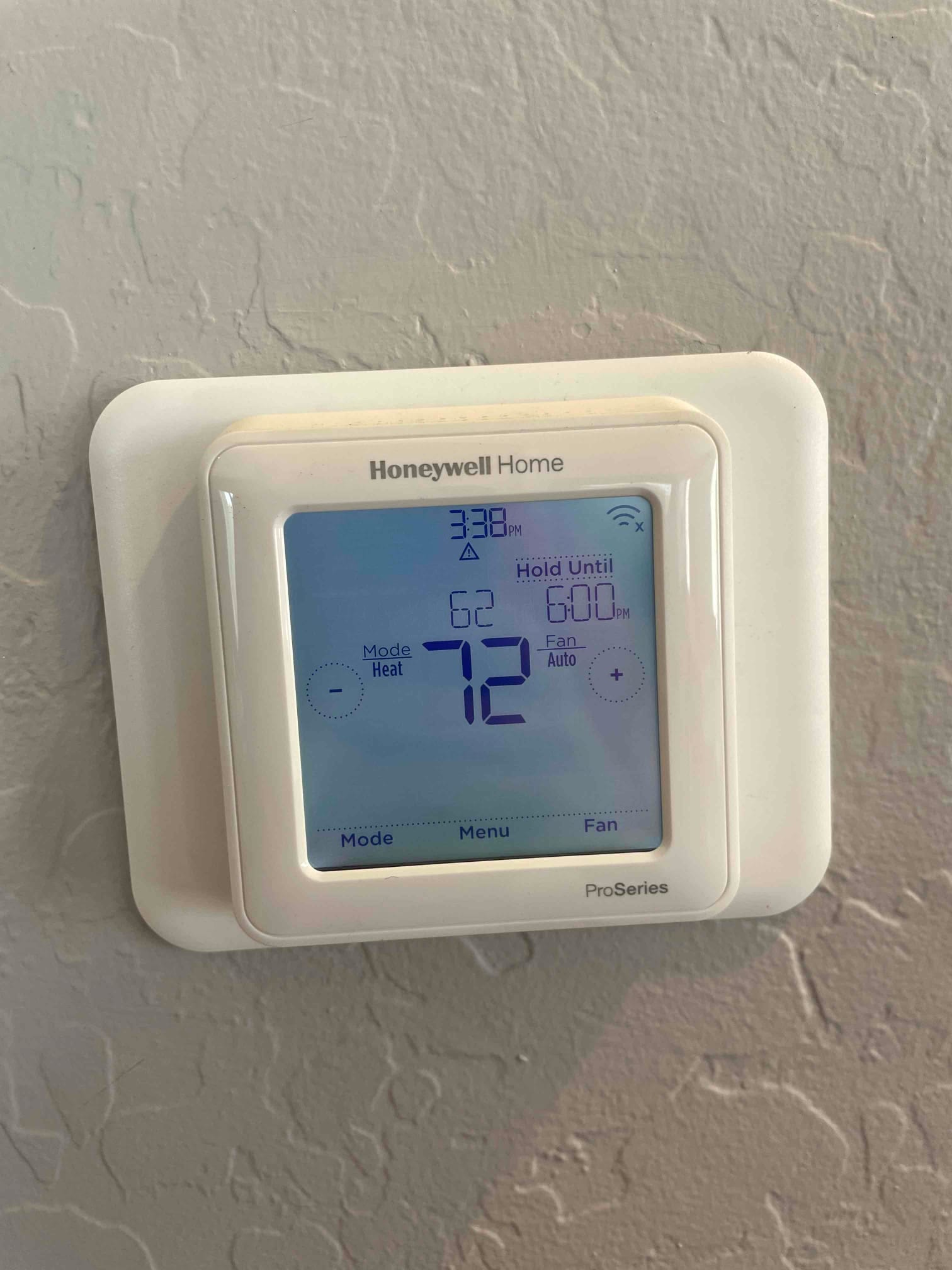 Wall-mounted digital thermostat installed and powered, display reading 72 degrees with fan set to Auto.
