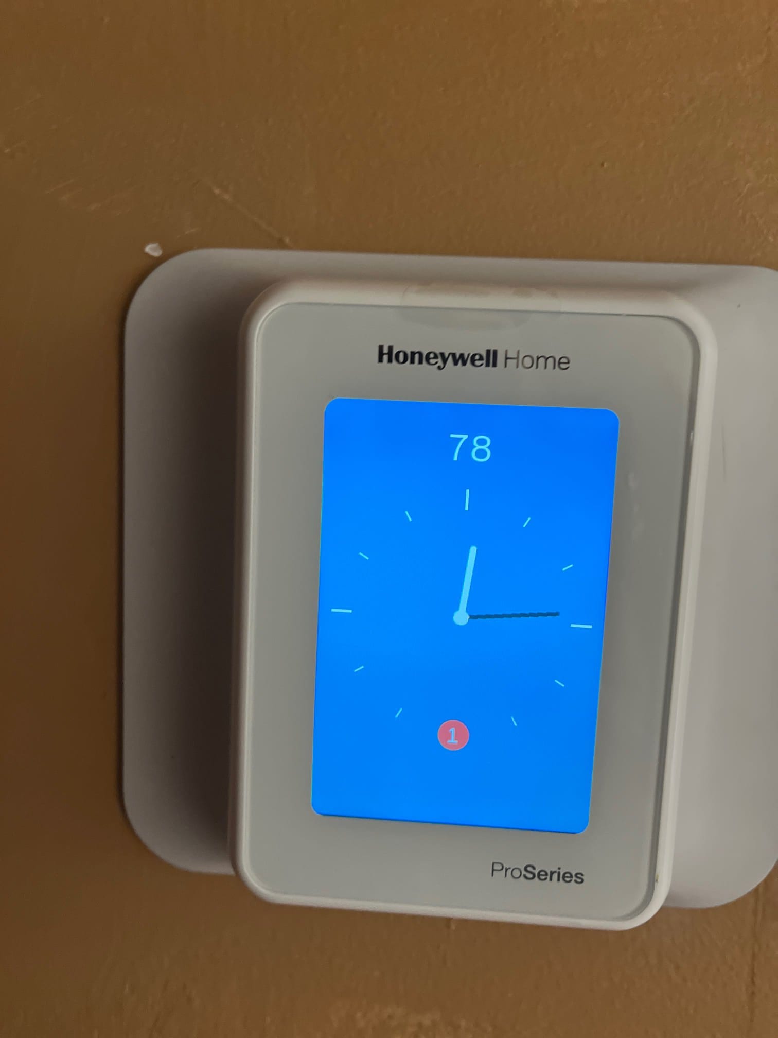 Wall-mounted digital thermostat installed and powered on, displaying 78 degrees with a notification icon on the home screen.