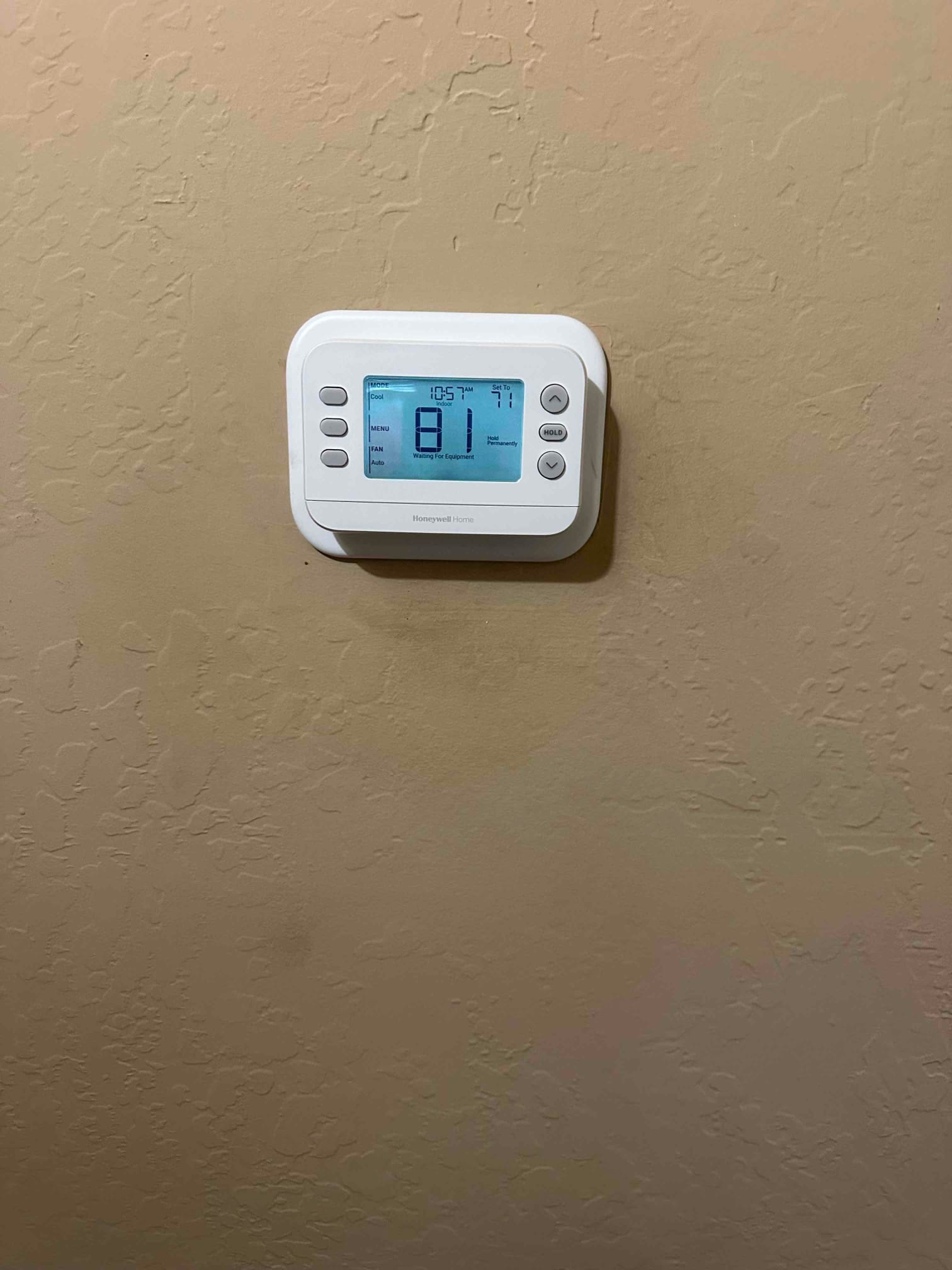Wall-mounted digital thermostat installed and powered on, displaying indoor temperature and cooling mode status.