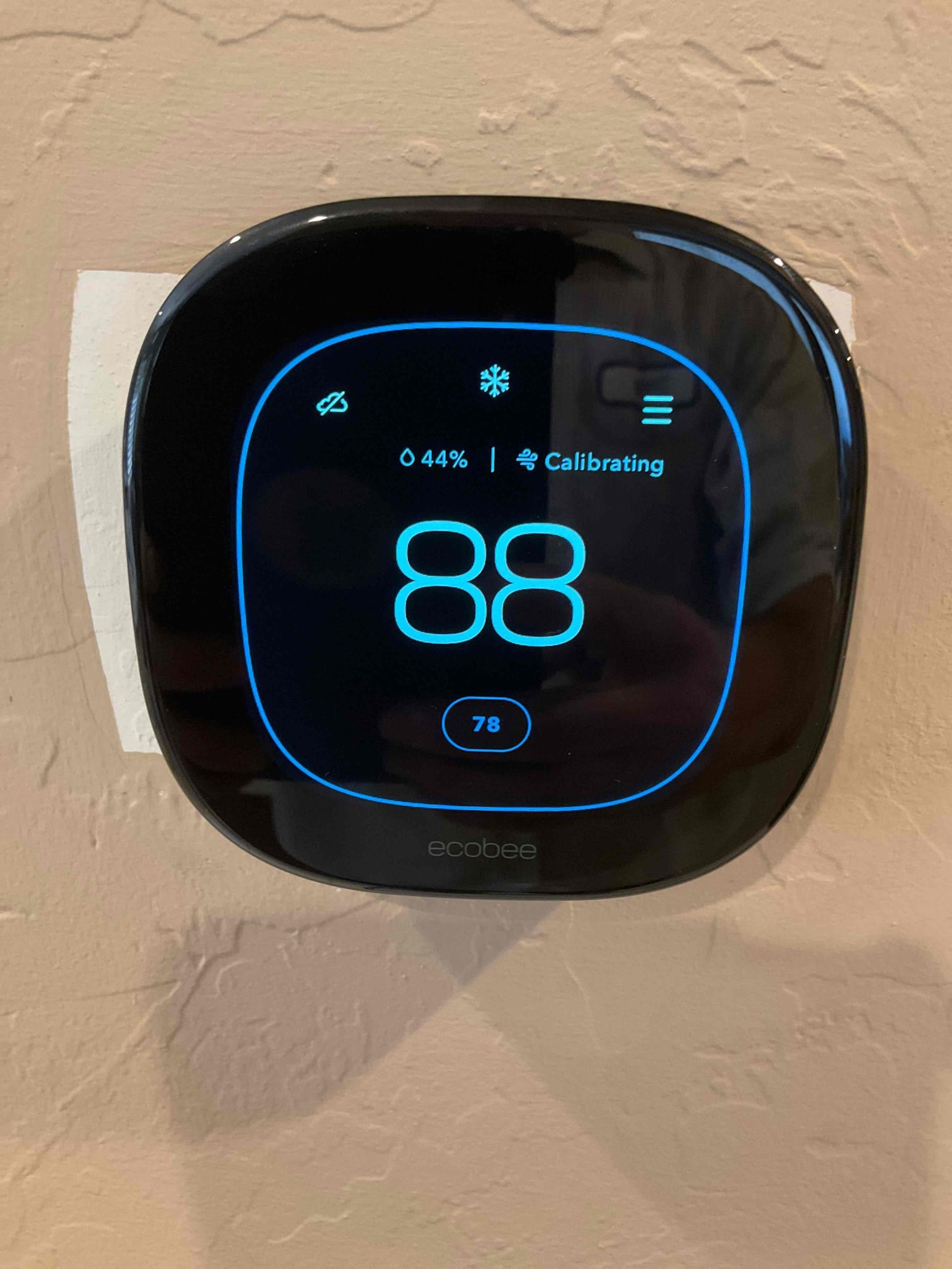 Wall-mounted smart thermostat displays 88 with cooling mode icon and shows system calibrating after installation.