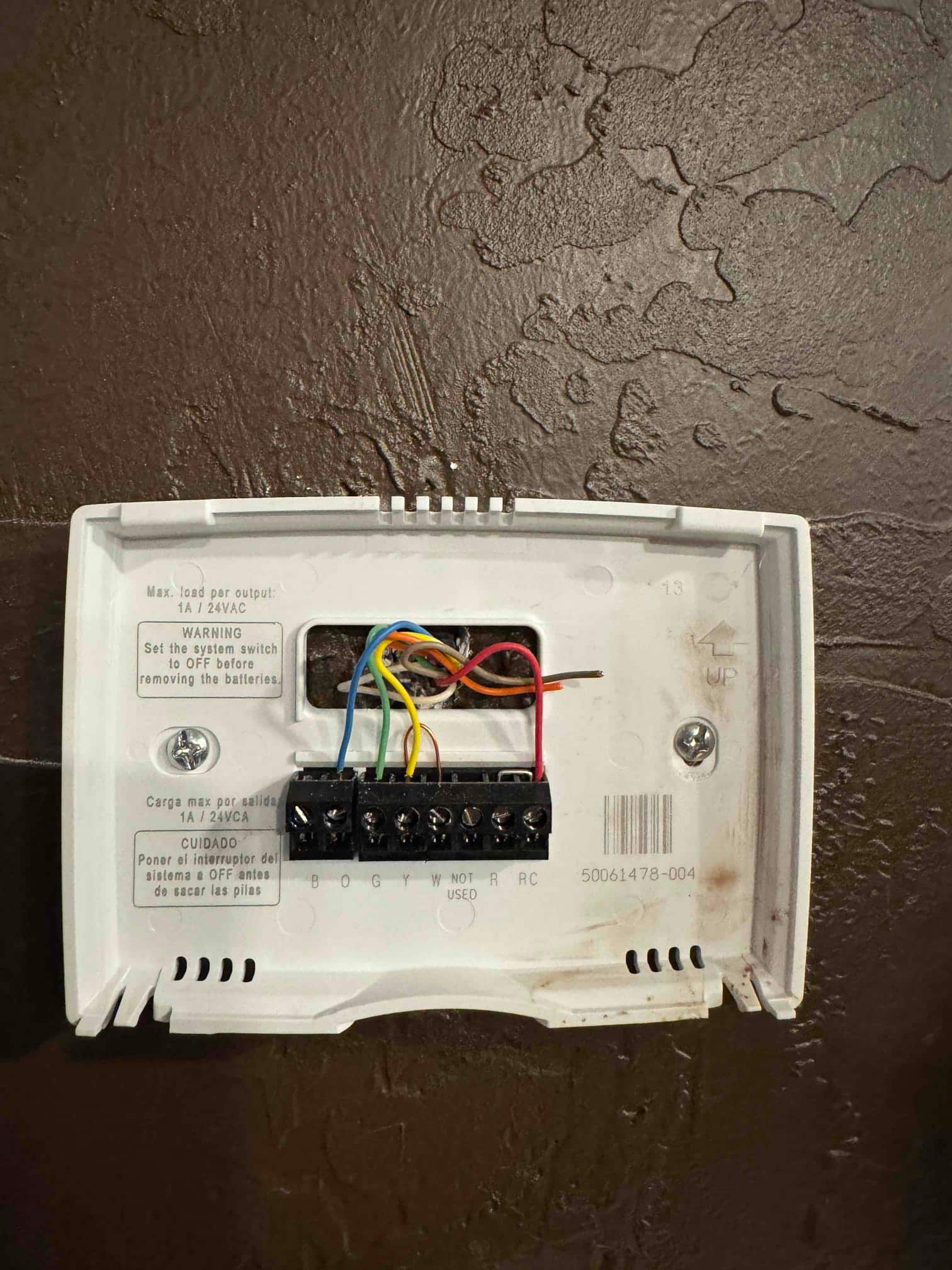 Wall-mounted thermostat with cover removed shows connected control wiring to R, Y, G, W, and C terminals.