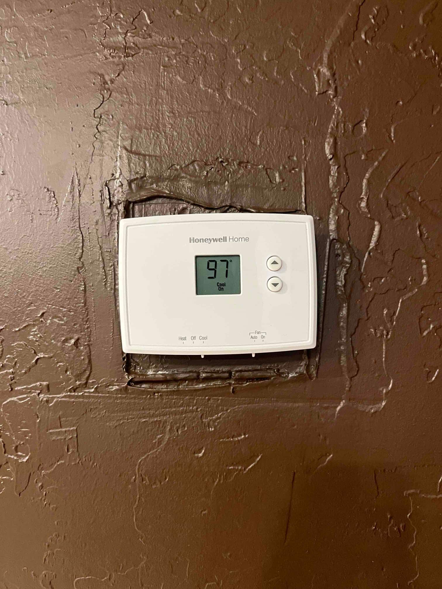 Wall-mounted thermostat displays 97 °F room temperature with system set to Cool and Fan set to Auto.