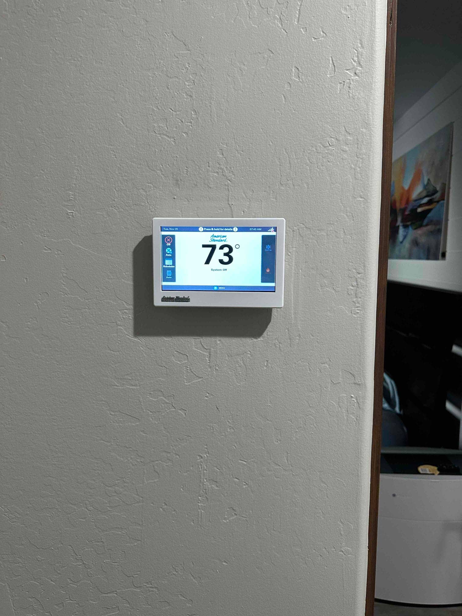 Wall-mounted touchscreen thermostat installed and powered, displaying an indoor temperature reading of 73 degrees with the system off.
