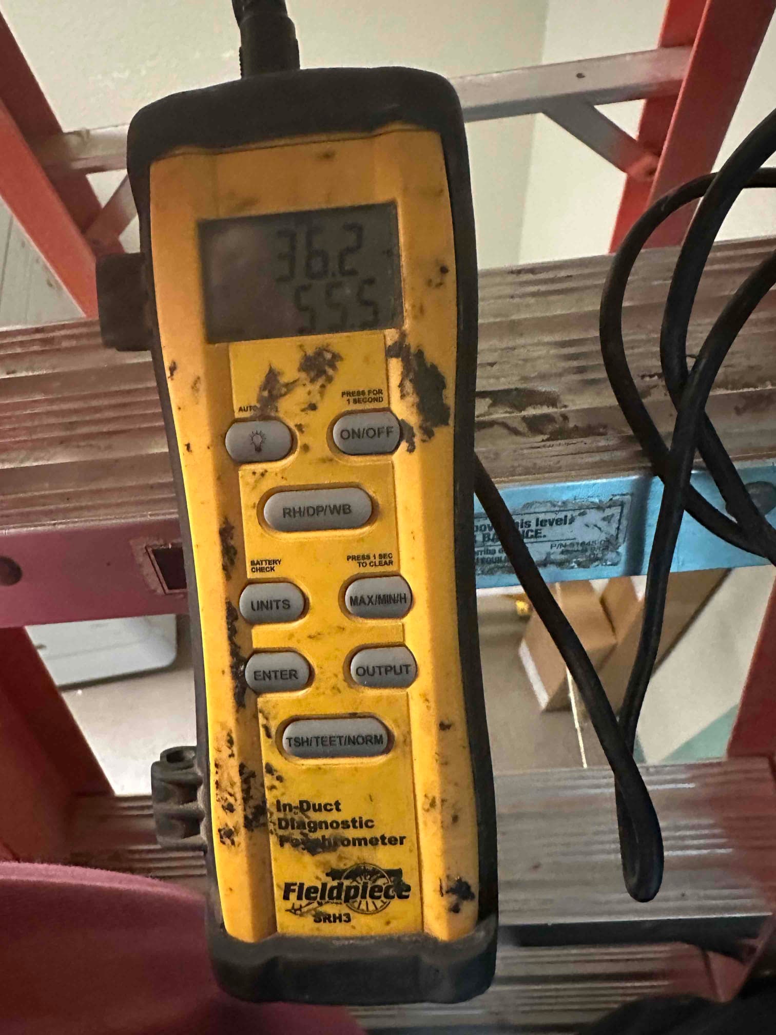 Digital in-duct thermometer displays 55.5 degrees Fahrenheit, documenting cooled supply air during commissioning.