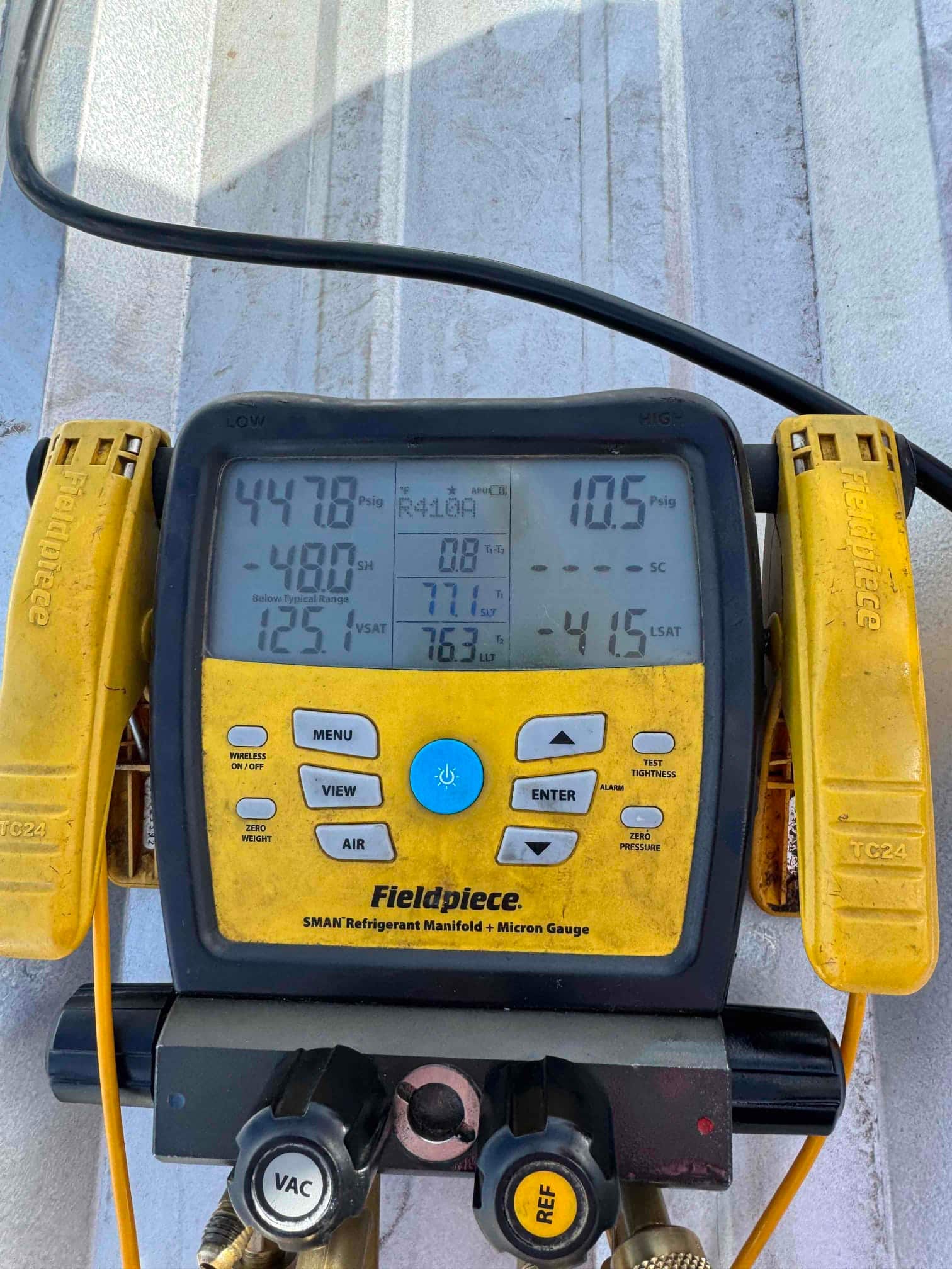 Digital manifold shows operating pressures with low side at 447.8 PSI and high side at 10.5 PSI while connected to the system.