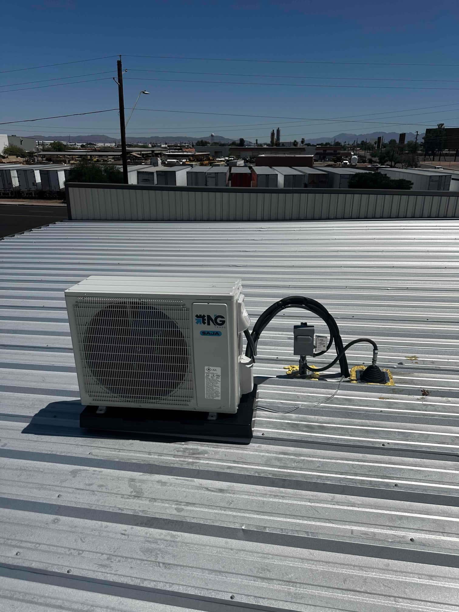 Mini-split outdoor condenser mounted on a rooftop pad with insulated line set and weather-sealed electrical disconnect penetration.