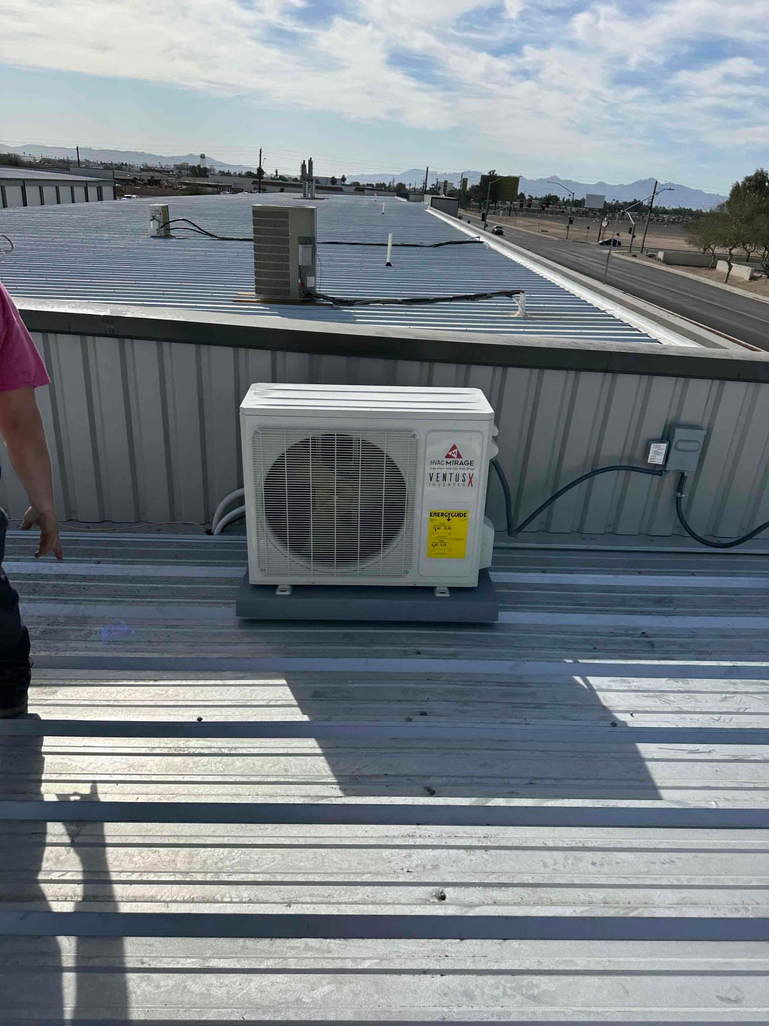 Mini-split outdoor condenser set on a rooftop pad with secured line set and electrical disconnect mounted nearby.