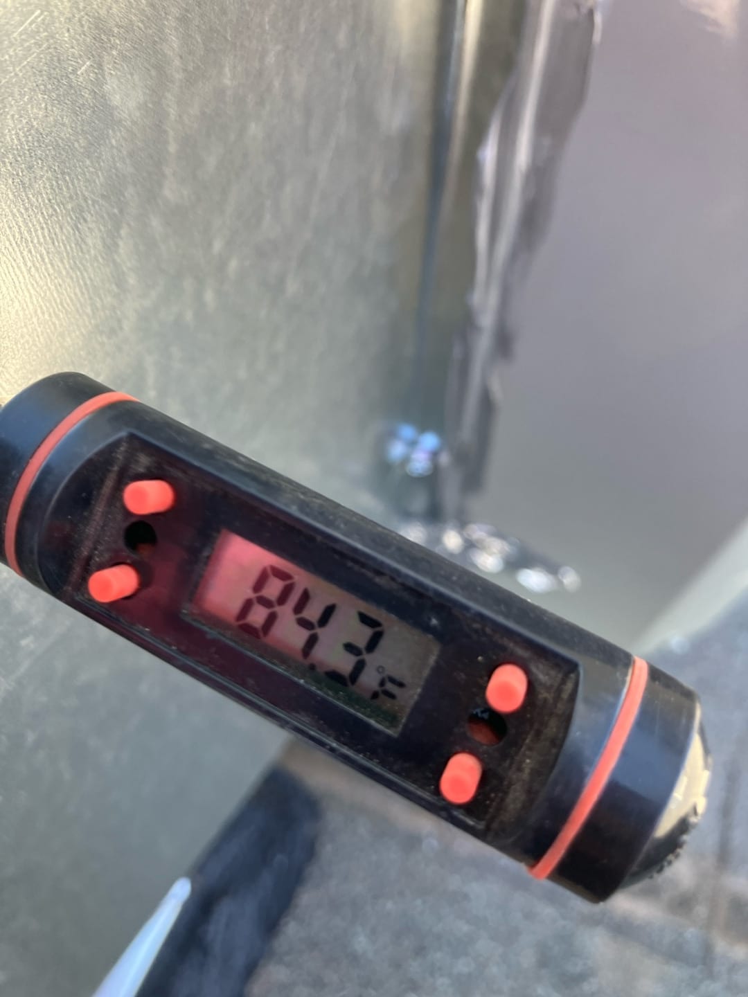 Digital thermometer displays 84.3°F while measuring air temperature during system air-side checks.