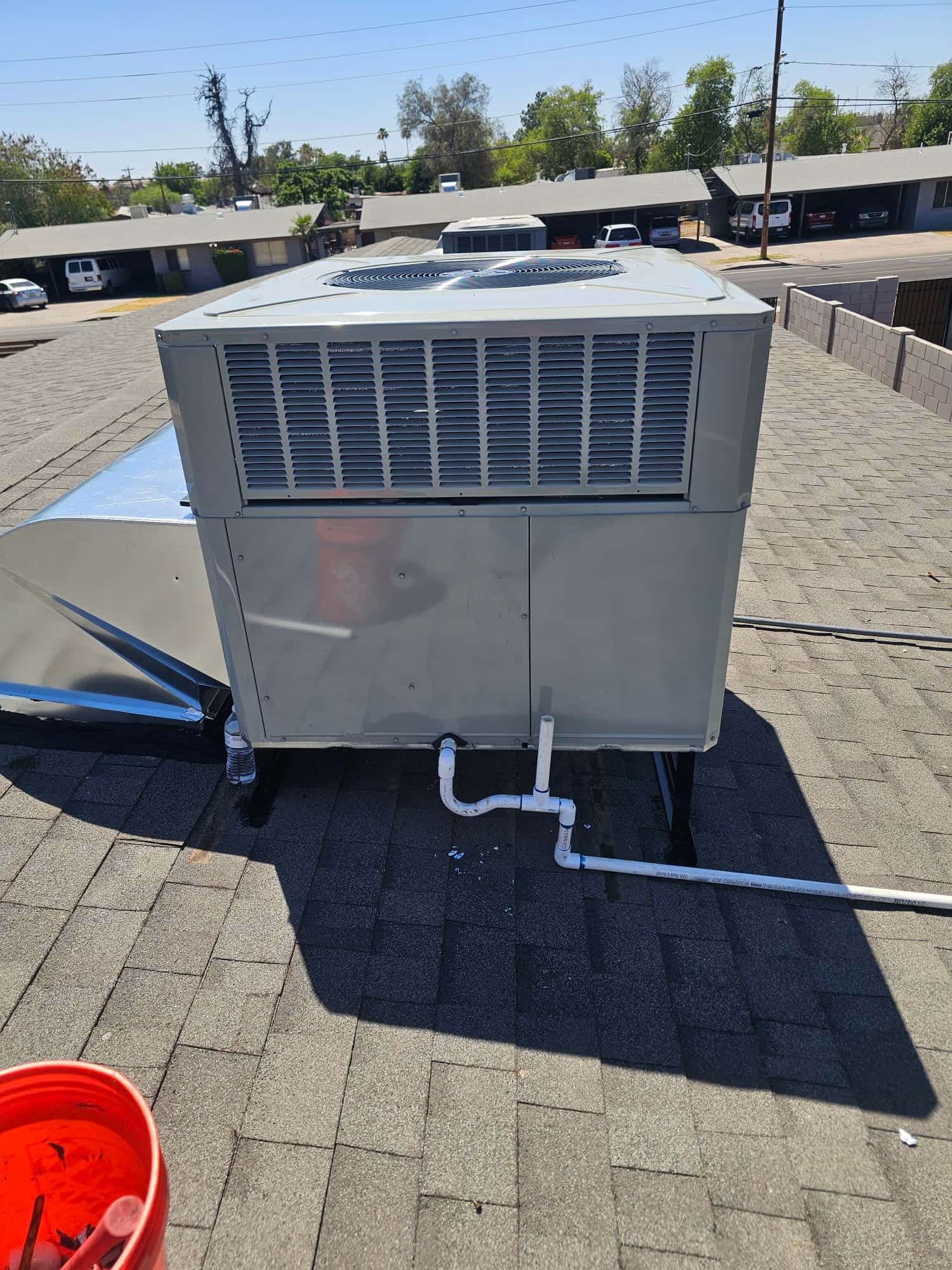 New packaged rooftop HVAC unit set on stands with connected condensate drain piping and sealed duct transition.