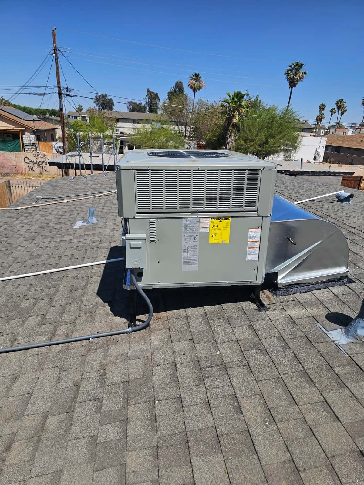 New rooftop packaged unit installed on shingles with sealed curb, electrical conduit, and sheet metal supply/return transition.