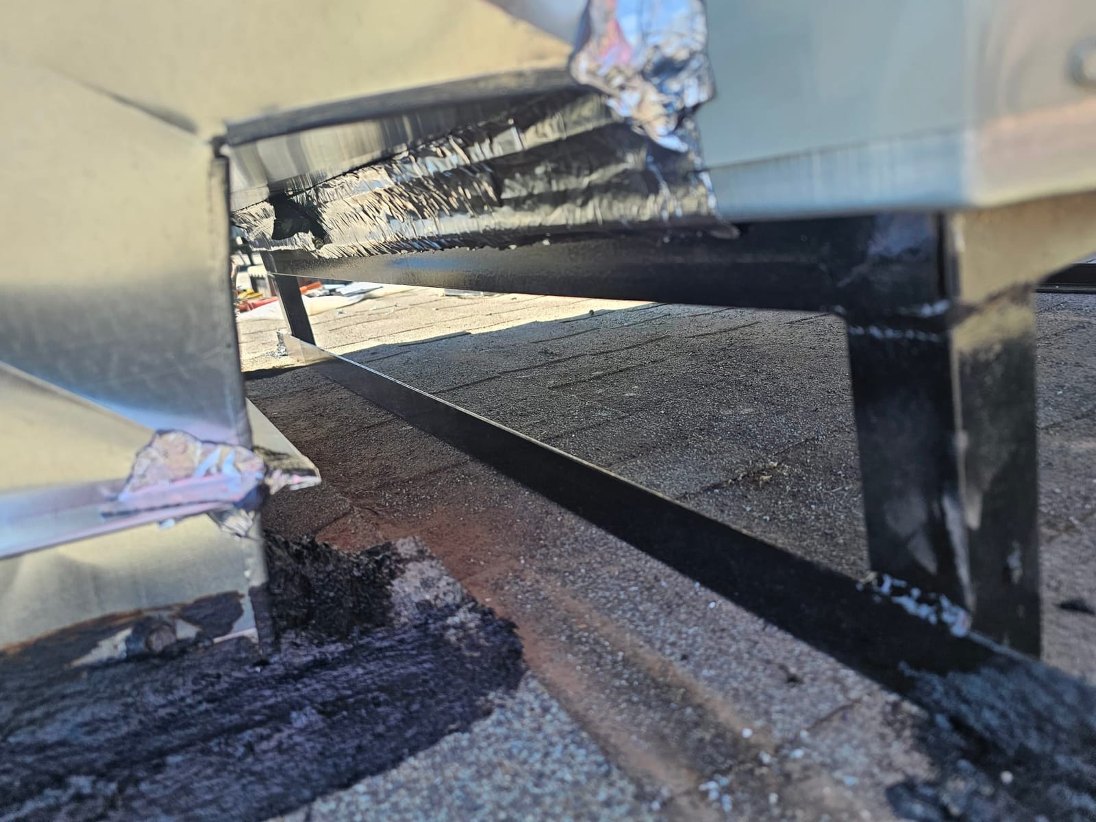 Rooftop equipment curb and support rails set in place with sealed roofing around the penetration.