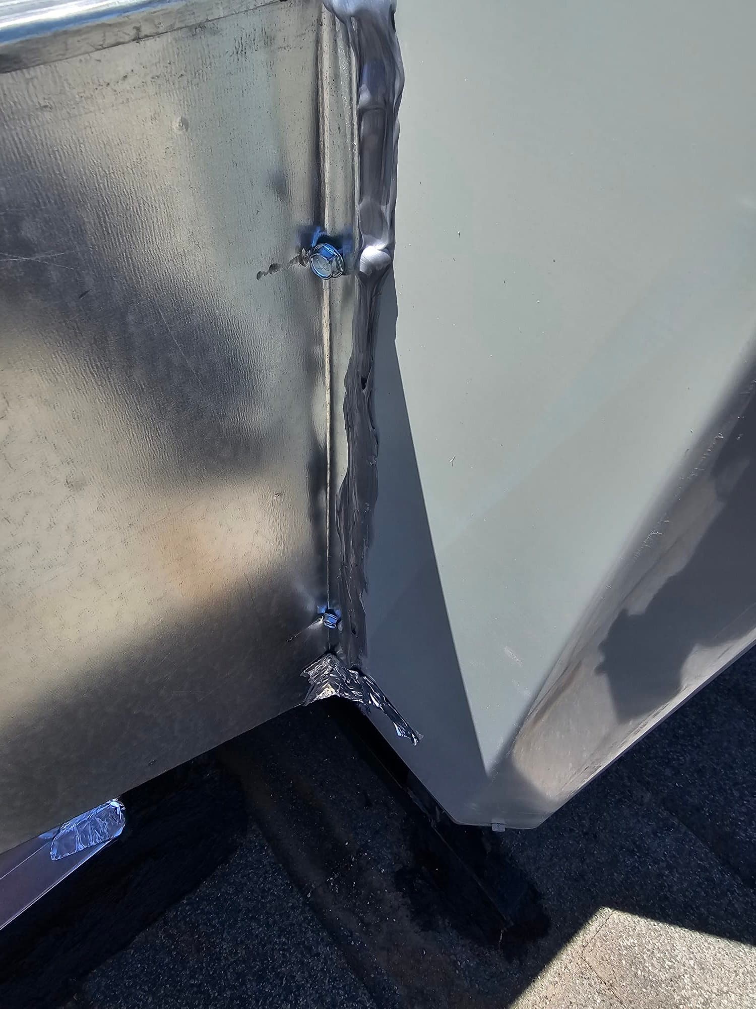 Sheet metal curb or duct transition sealed with mastic and fasteners on the rooftop during HVAC installation.