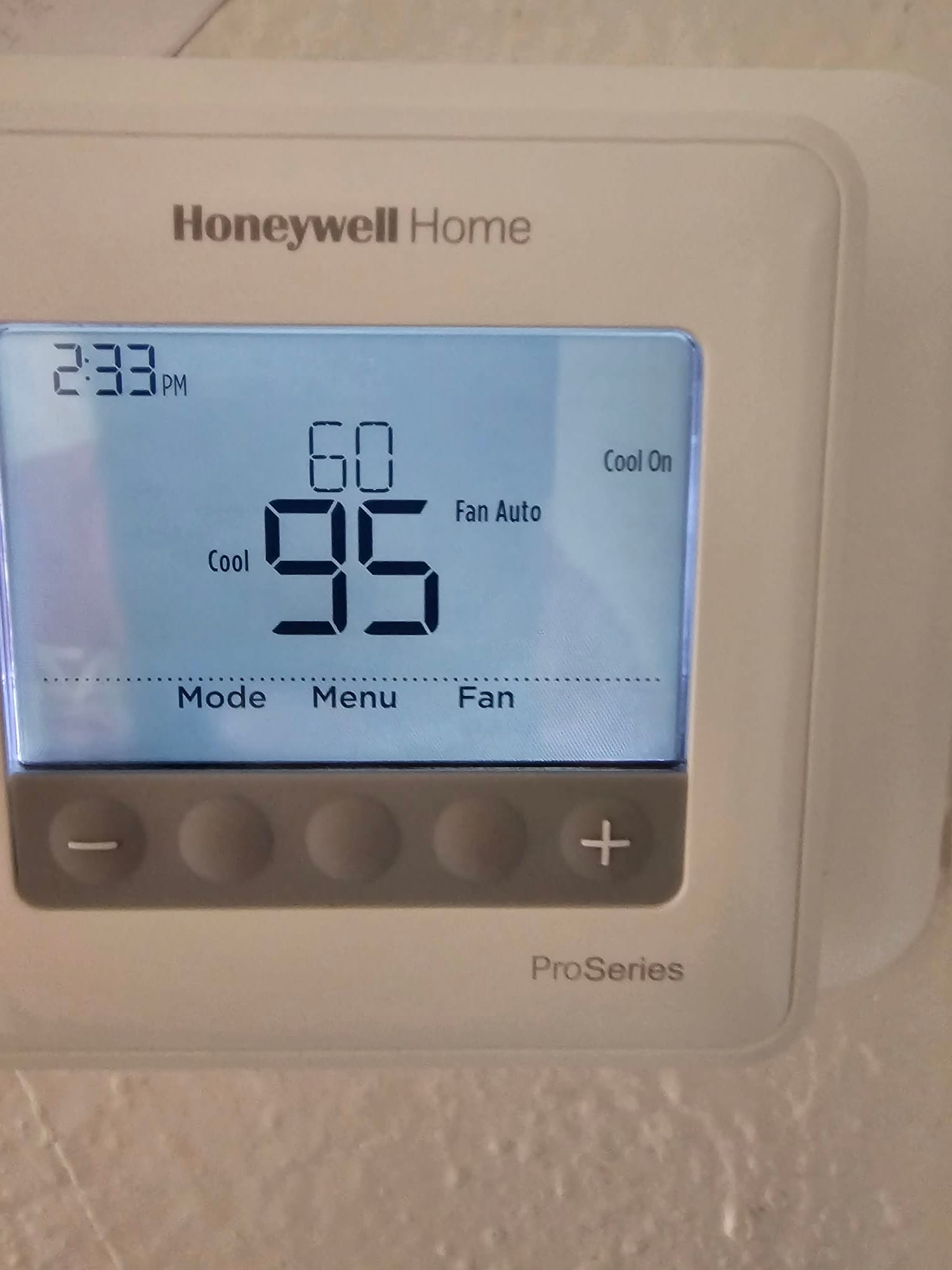 Wall-mounted programmable thermostat set to Cool with a 60°F setpoint and Fan Auto displayed on the screen.