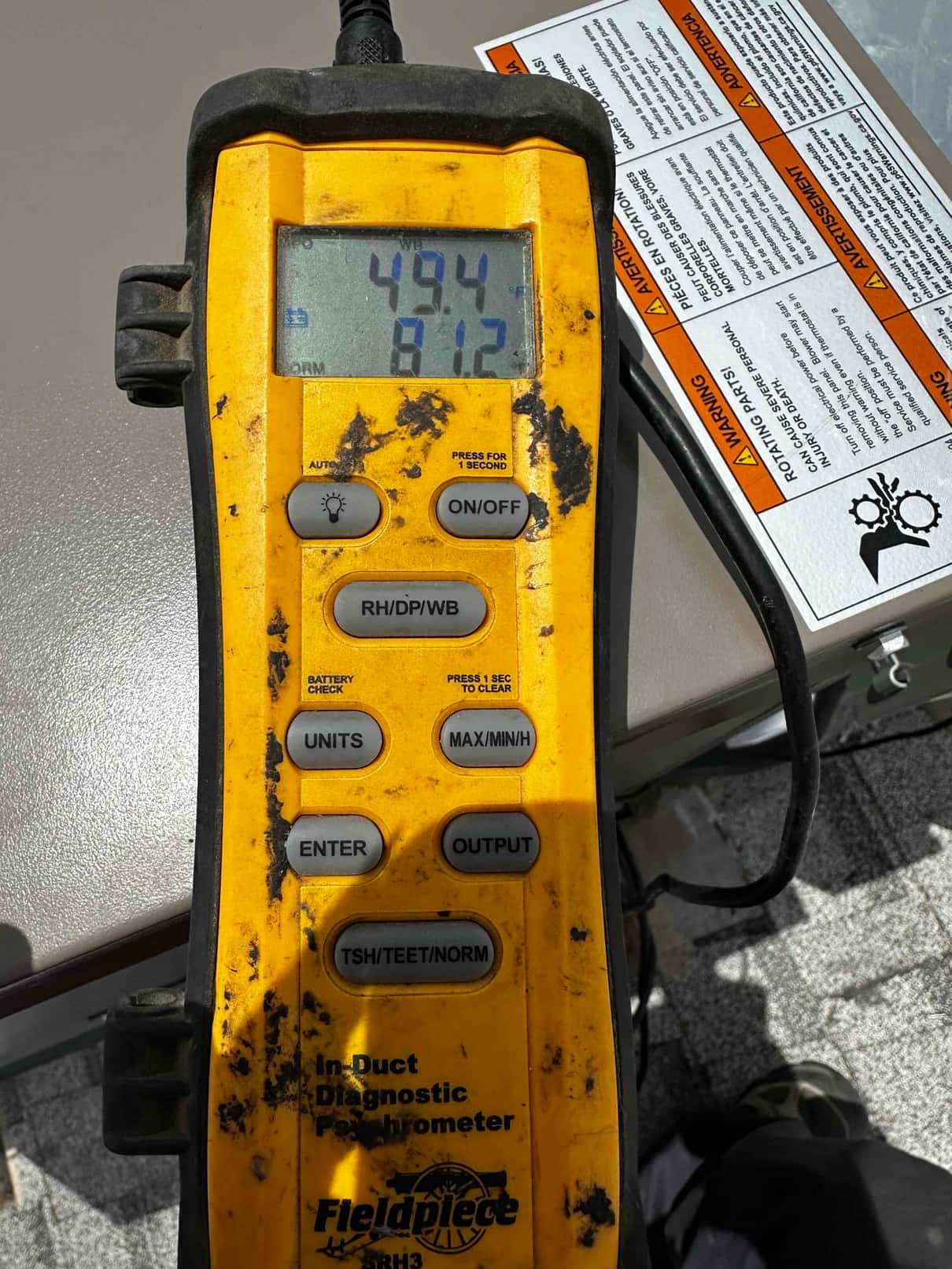 Digital psychrometer shows supply air temperature at 49.4°F, documenting cooled air leaving the evaporator during commissioning.