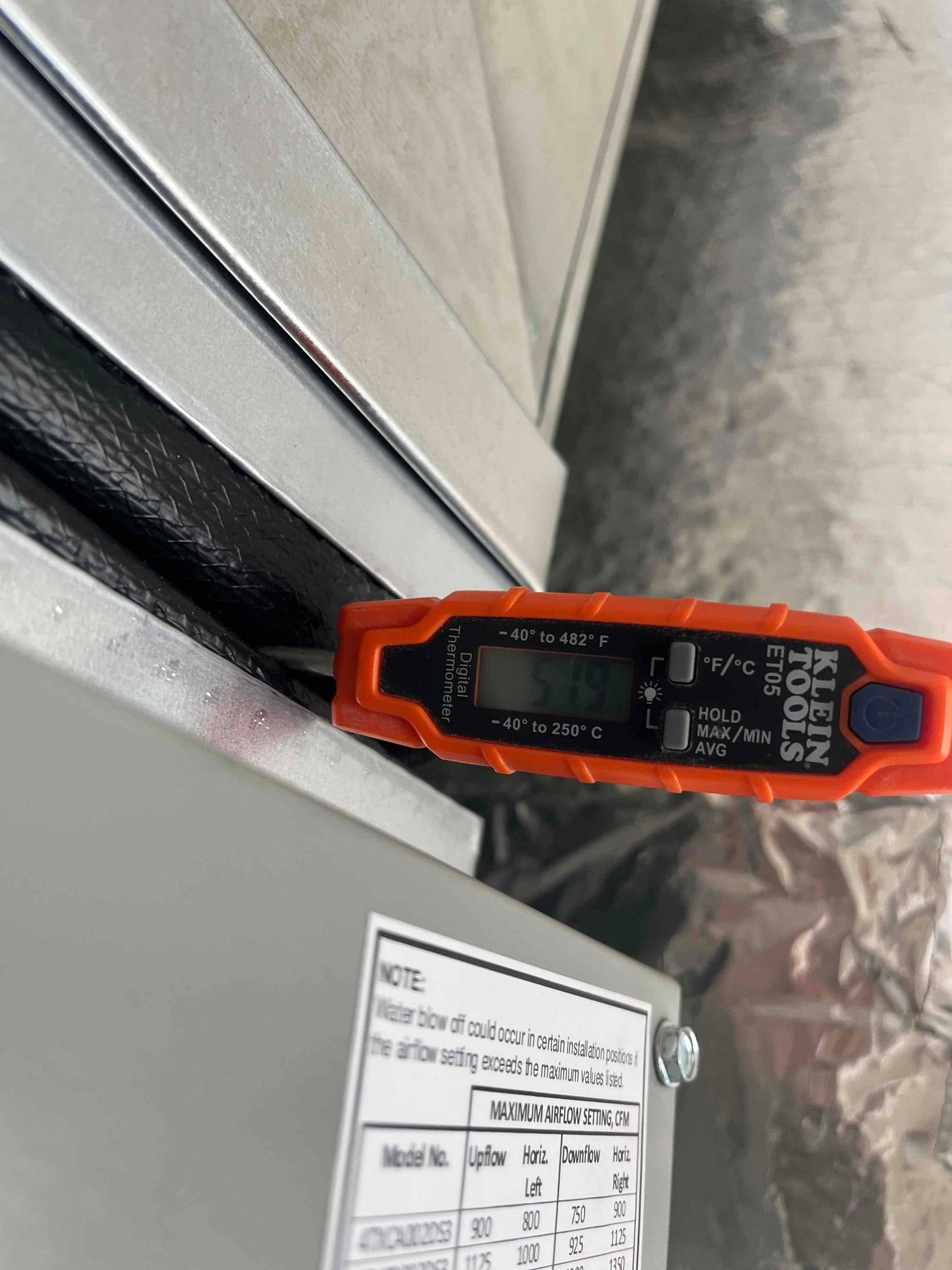 Digital thermometer inserted at the supply plenum shows a cold air temperature of 51°F during cooling operation.