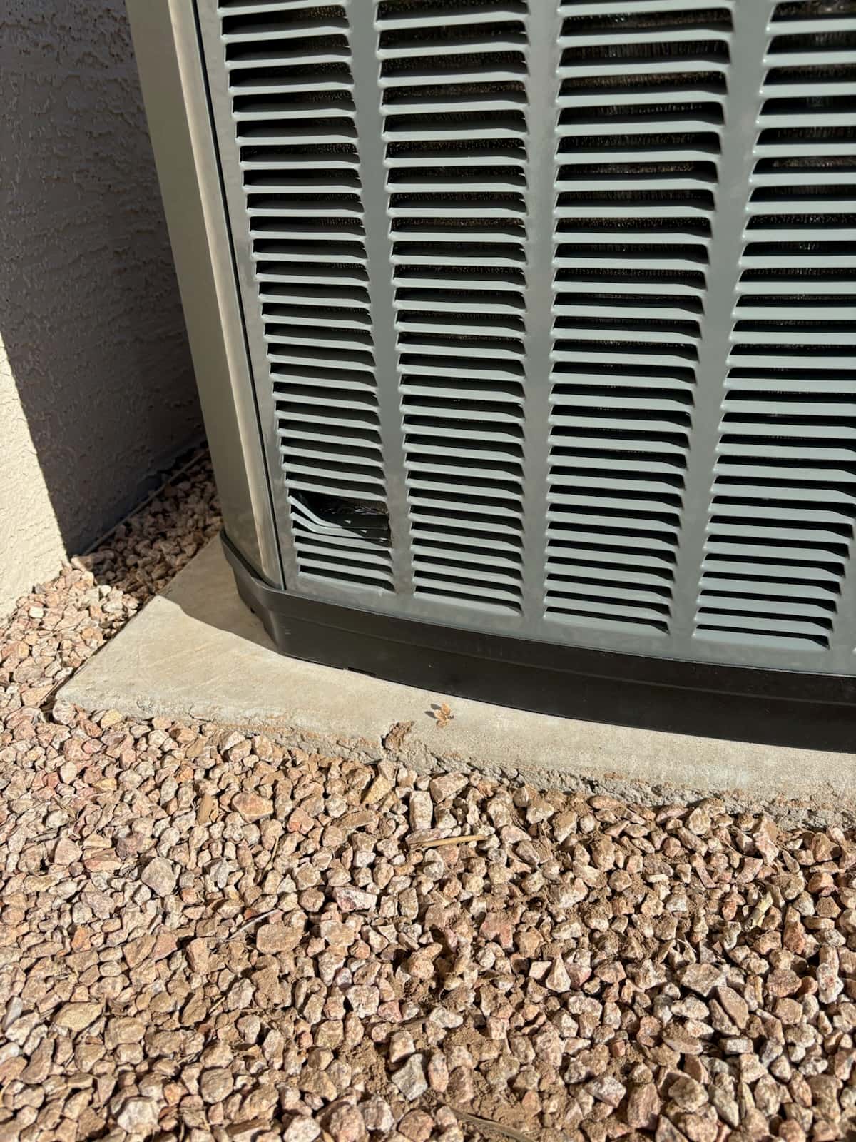 Outdoor condenser cabinet set on a level concrete pad with gravel surrounding the installation area.