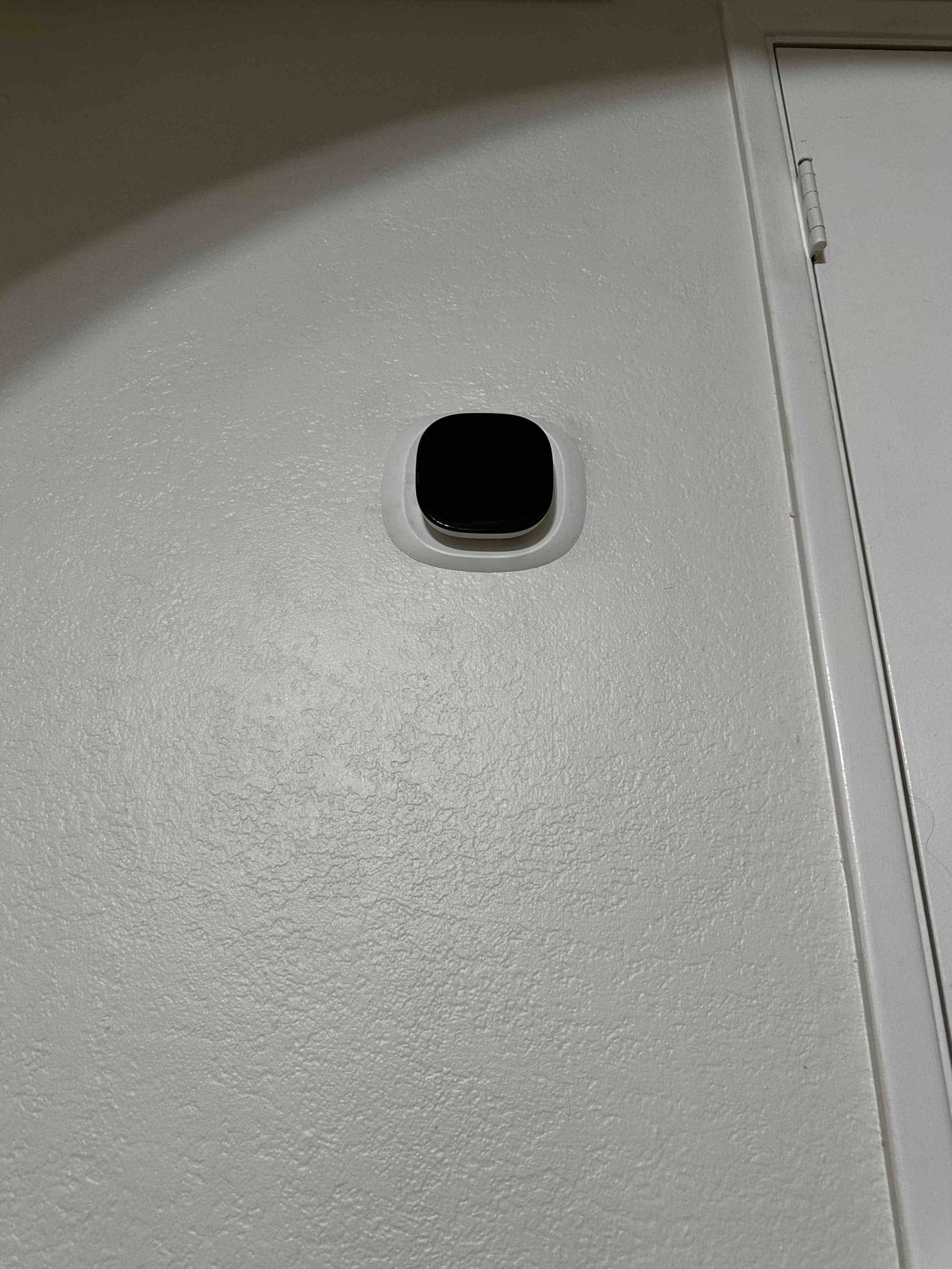 Wall-mounted thermostat installed with trim plate near a door frame, part of the new HVAC control setup.