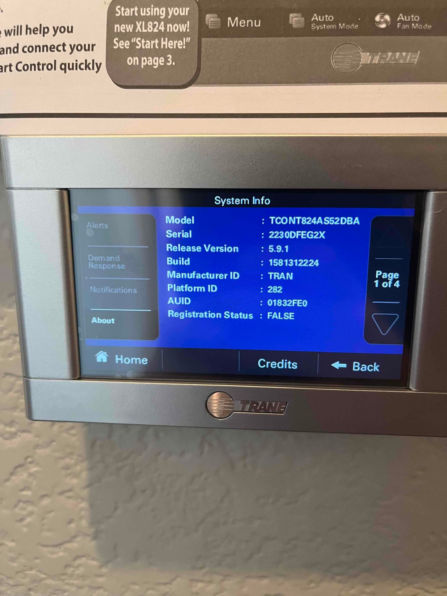 Wall-mounted touchscreen thermostat displays system information menu after installation, with on-screen navigation and status details visible.