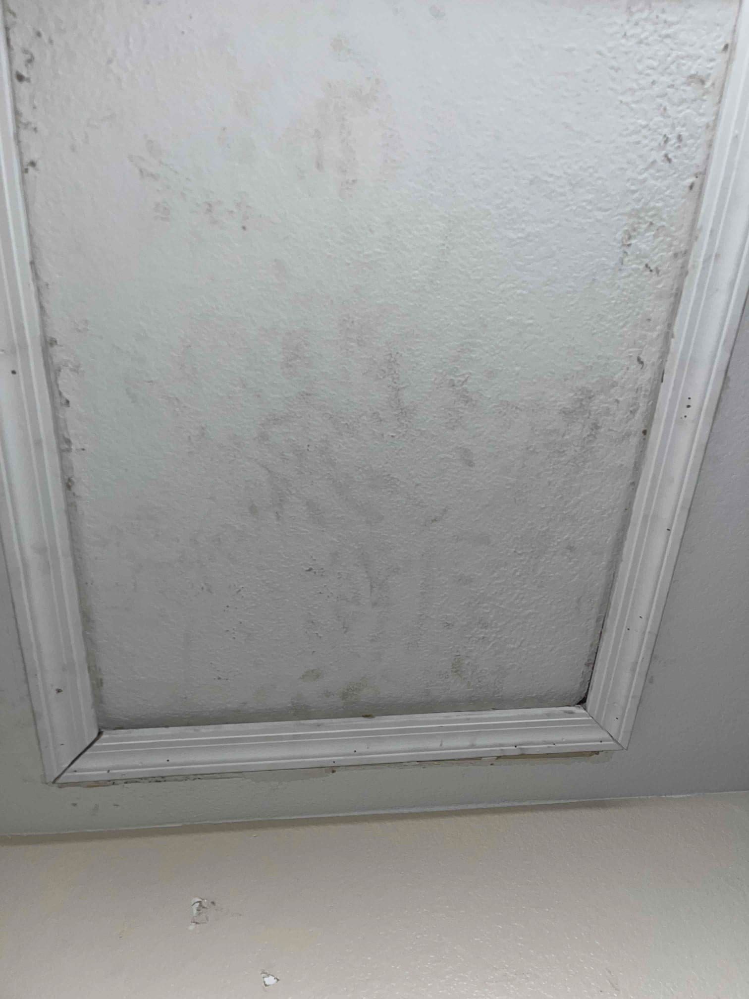 Attic access panel with trim showing dirt and scuffs at the installation site near the indoor equipment area.