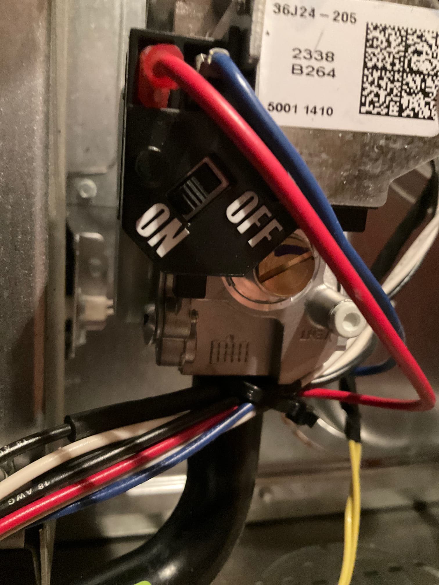 Close-up of a furnace gas valve assembly with ON/OFF switch and connected control wiring inside the cabinet.