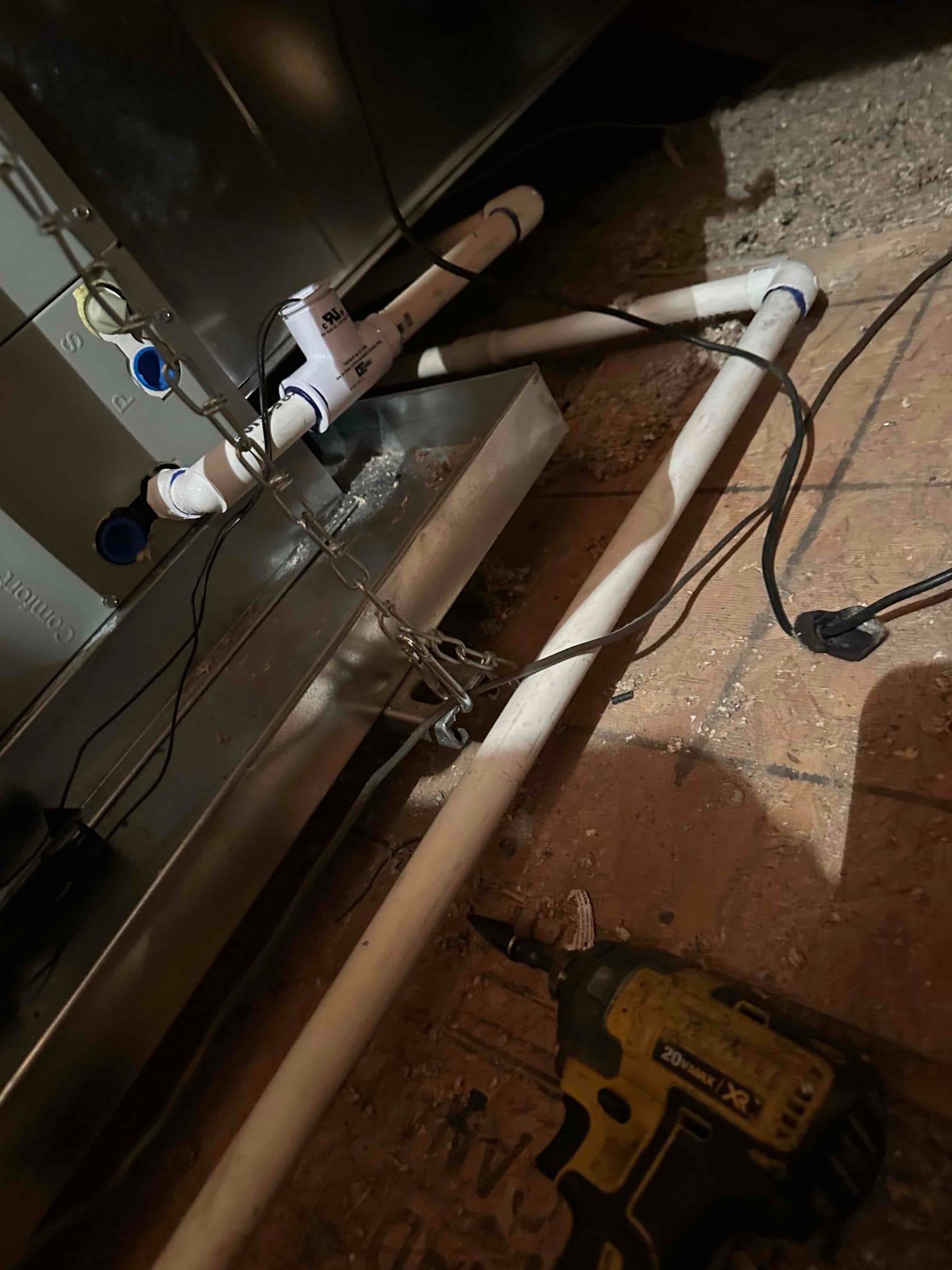 Condensate drain piping with cleanout tee and trap connected to the air handler over a secondary drain pan in the attic.