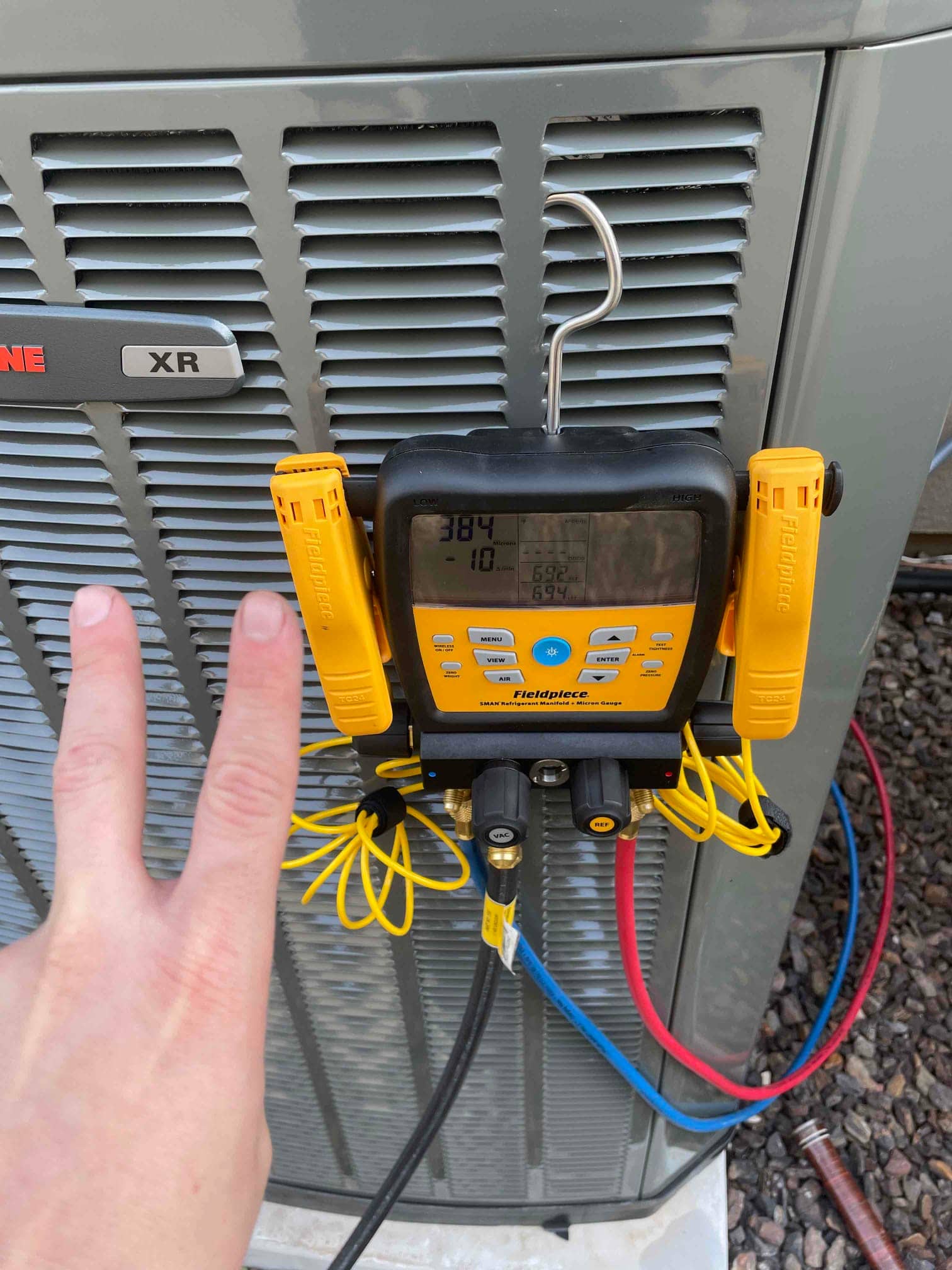 Digital manifold attached to the outdoor condenser shows equal pressures near 384 PSI on both sides during a nitrogen pressure test.