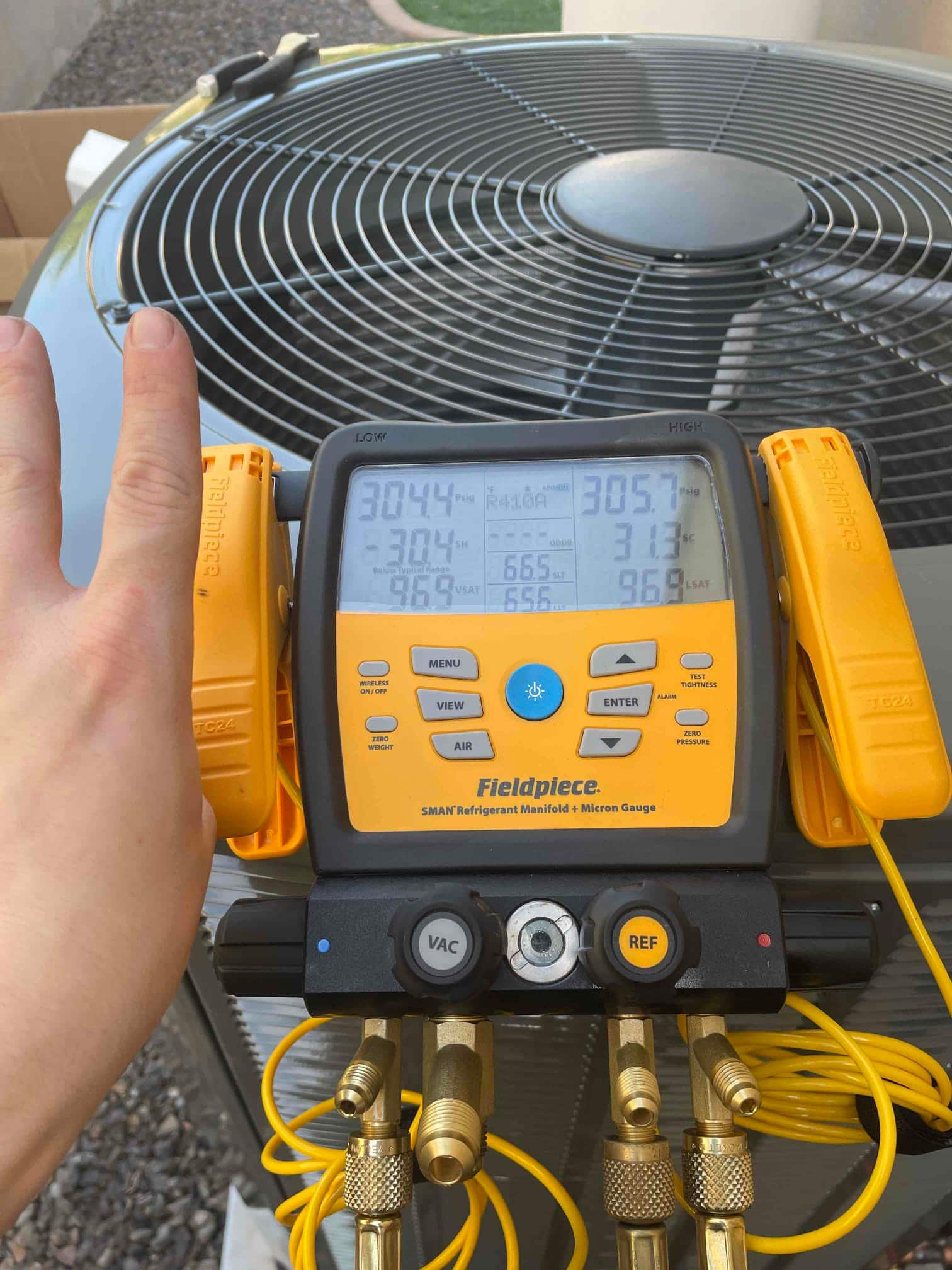 Digital manifold connected at the outdoor unit shows equalized pressures around 304–305 PSI during a nitrogen pressure test.