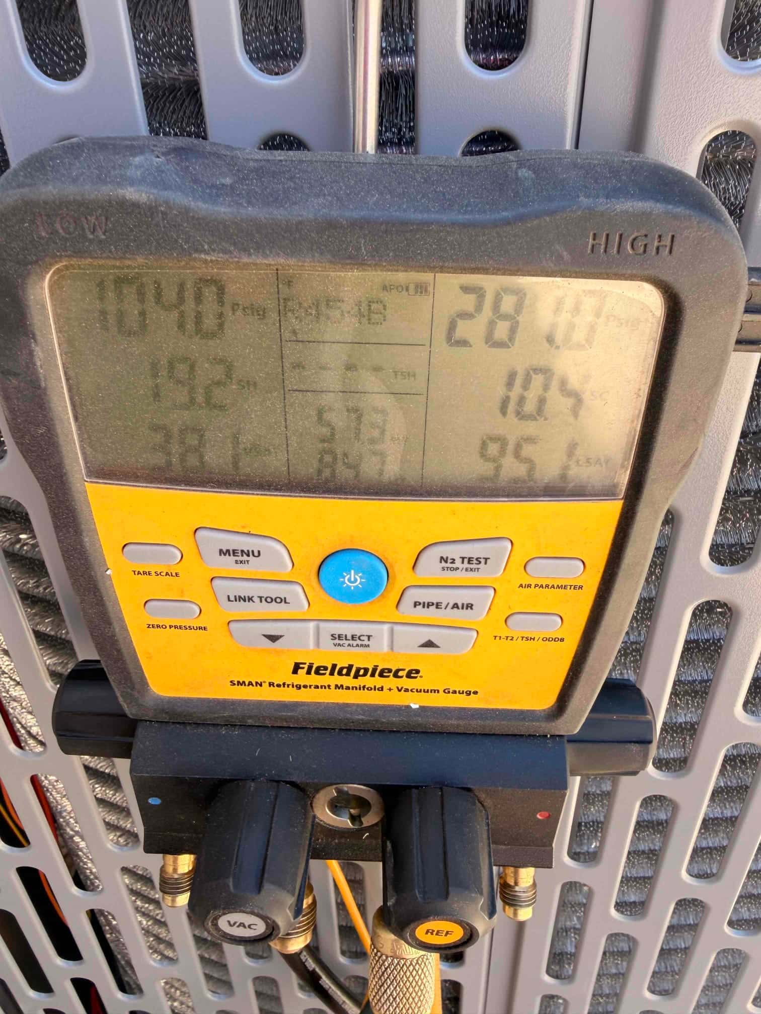 Digital manifold connected at the outdoor unit shows operating refrigerant pressures during system commissioning.